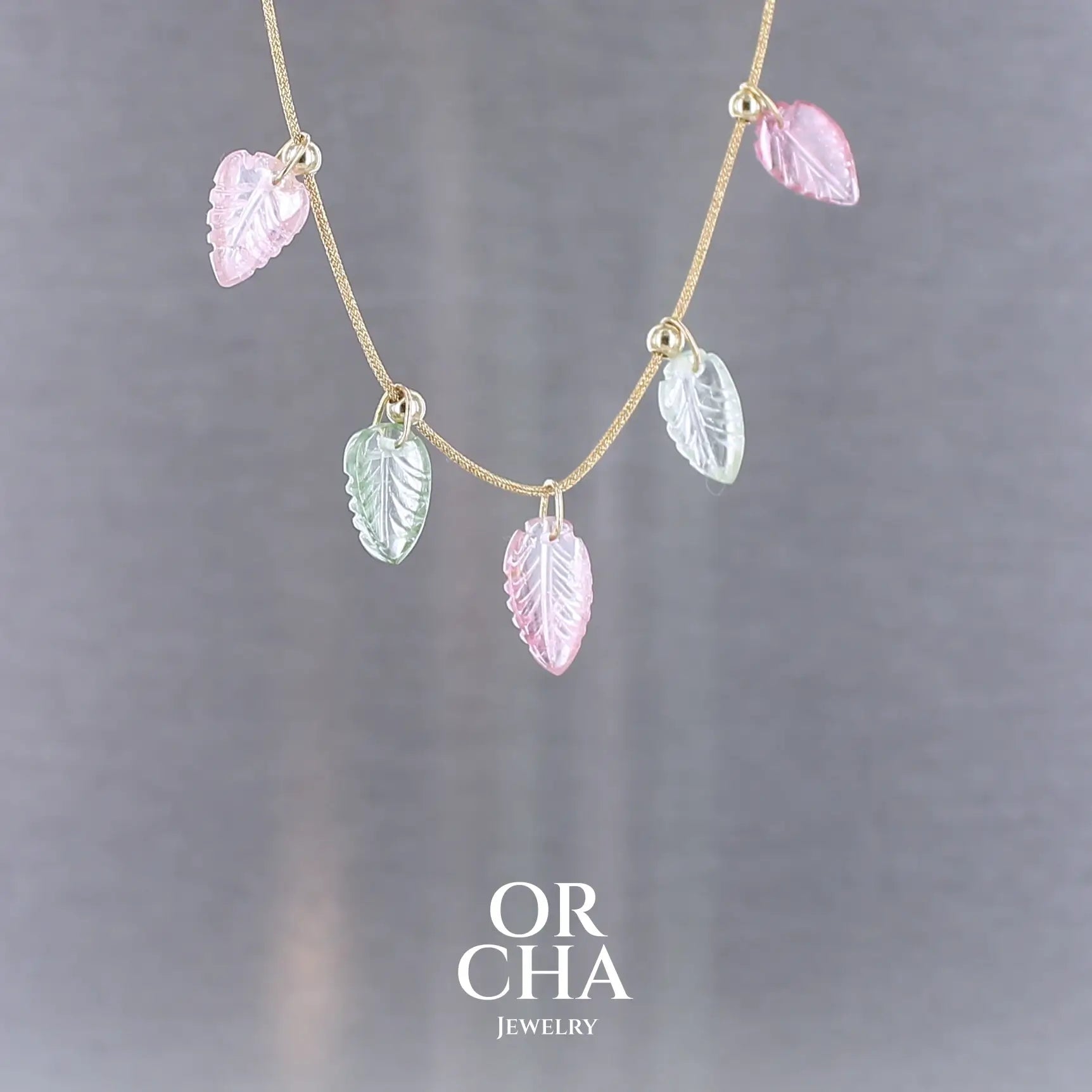 Collier pour femme orné de tourmalines roses et vertes sculptées à la main en 3 dimensions en forme de feuilles serties en or 18k. Les breloques sont montées sur un collier corde doré scintillant, les apprêts utilisé sont en Gold filled ( or laminé ). Longueur ajustable de 40 cm à 45 cm. Bijoux unique, éthique et durable présenté dans un coffret de notre marque, prêt à offrir. Livraison offerte, certificat d'authenticité, service client.