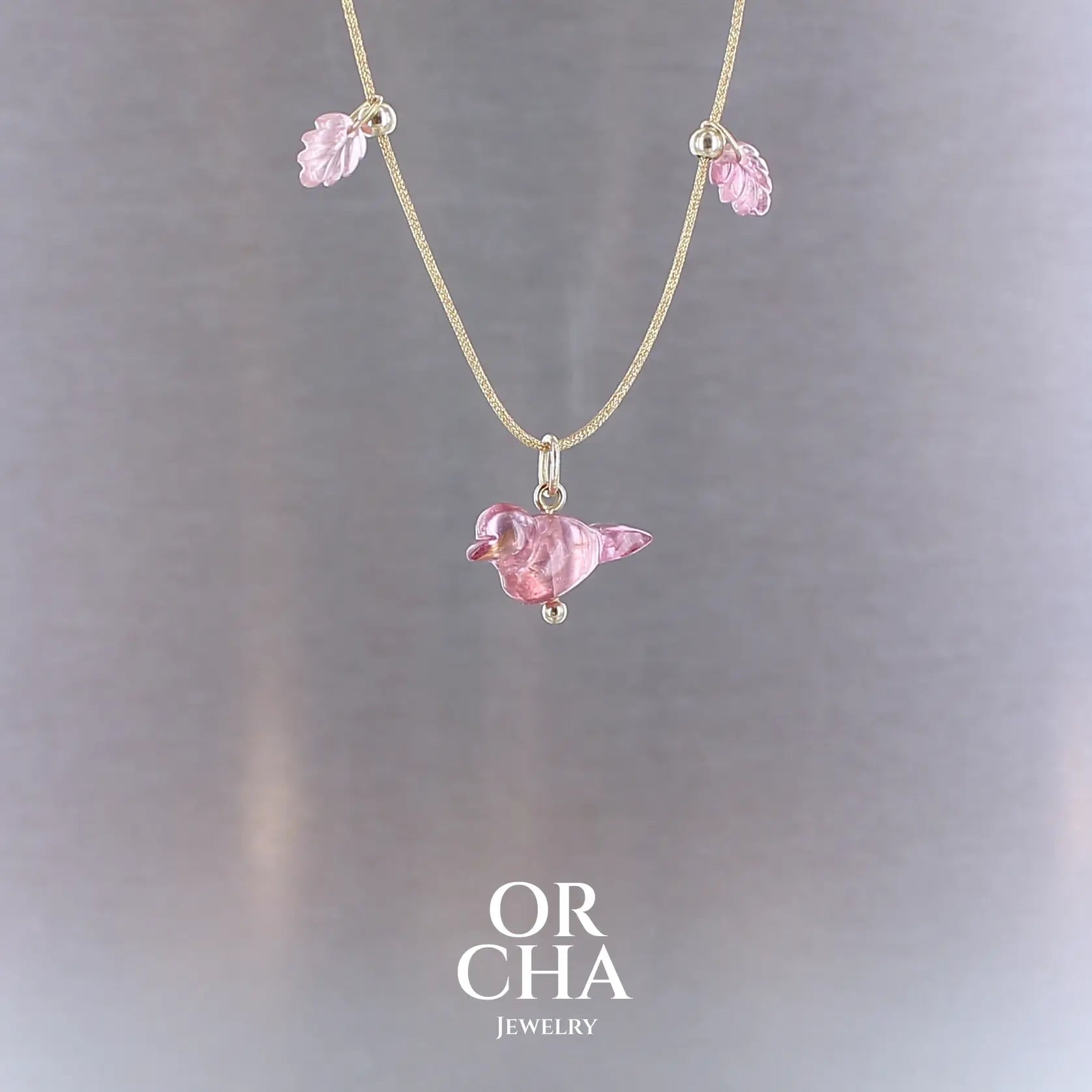 Collier pour femme orné de tourmalines roses sculptées à la main en 3 dimensions en forme d'oiseau et de feuilles, serties en or 18k. Les pendentifs sont montés sur un collier corde doré scintillant, les apprêts utilisé sont en Gold filled ( or laminé ). Longueur ajustable de 40 cm à 45 cm. Bijoux unique, éthique et durable présenté dans un coffret de notre marque, prêt à offrir. Livraison offerte, certificat d'authenticité, service client.