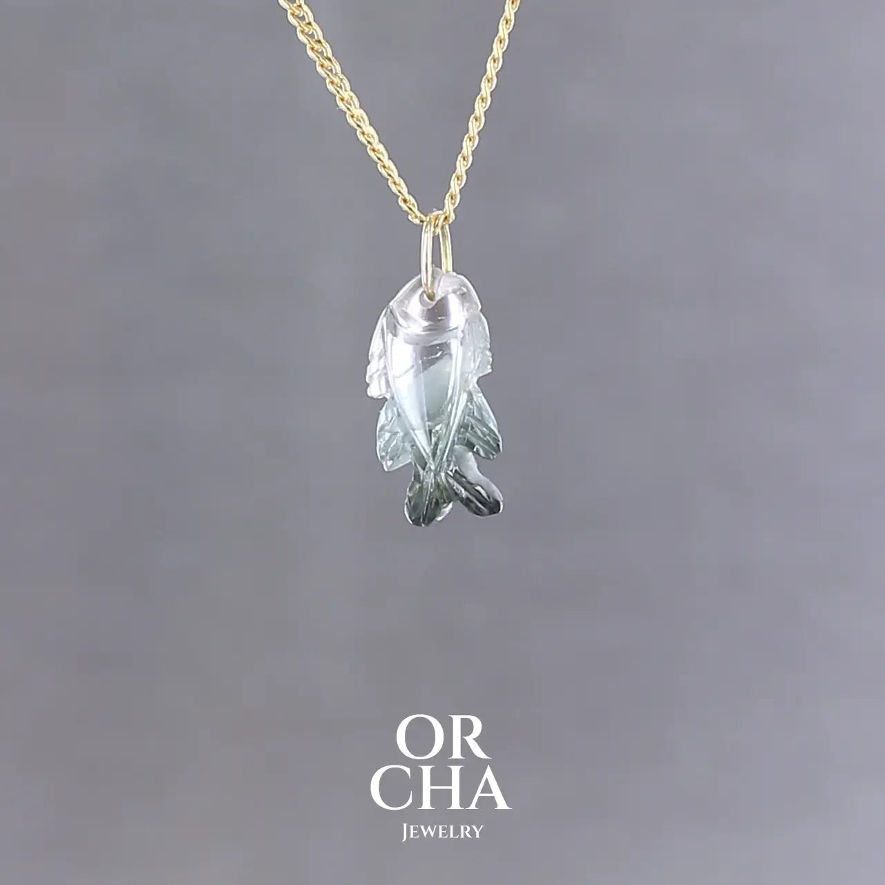 Collier pour femme orné d'une tourmaline bleue sculptée à la main en 3 dimensions en forme de poisson sertie en or 18k. Le pendentif est monté sur une chaine en Gold filled ( or laminé ) d'une longueur de 45 cm. Bijoux unique, éthique et durable présenté dans un coffret de notre marque, prêt à offrir. Livraison offerte, certificat d'authenticité, service client.