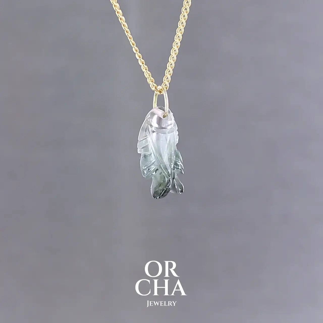 Collier pour femme orné d'une tourmaline bleue sculptée à la main en 3 dimensions en forme de poisson sertie en or 18k. Le pendentif est monté sur une chaine en Gold filled ( or laminé ) d'une longueur de 45 cm. Bijoux unique, éthique et durable présenté dans un coffret de notre marque, prêt à offrir. Livraison offerte, certificat d'authenticité, service client.