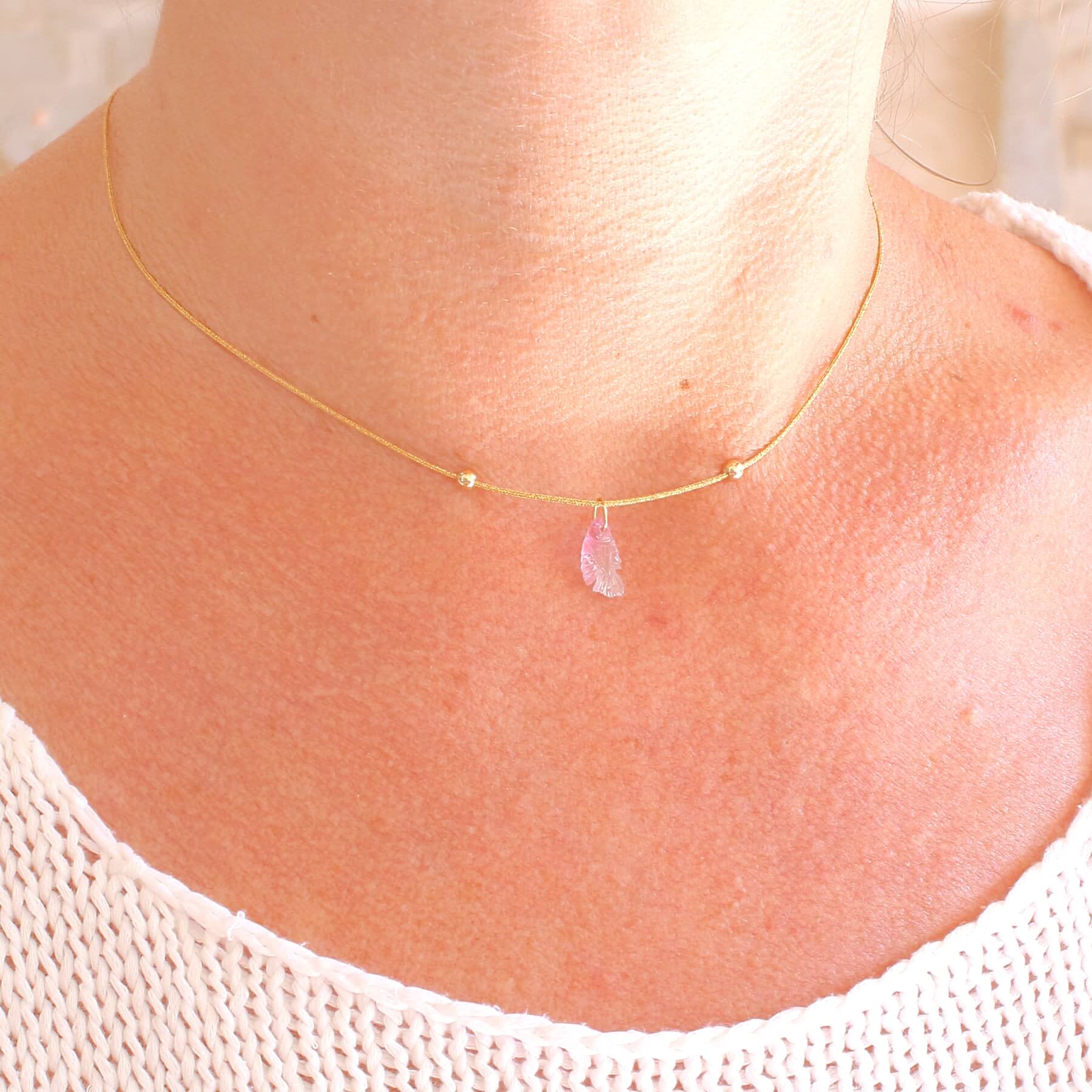 Collier pour femme orné d'une tourmaline rose sculptée à la main en 3 dimensions en forme de poisson sertie en or 18k. Le pendentif est monté sur un collier corde doré scintillant, les apprêts utilisé sont en Gold filled ( or laminé ). Longueur ajustable de 40 cm à 45 cm. Bijoux unique, éthique et durable présenté dans un coffret de notre marque, prêt à offrir. Livraison offerte, certificat d'authenticité, service client.