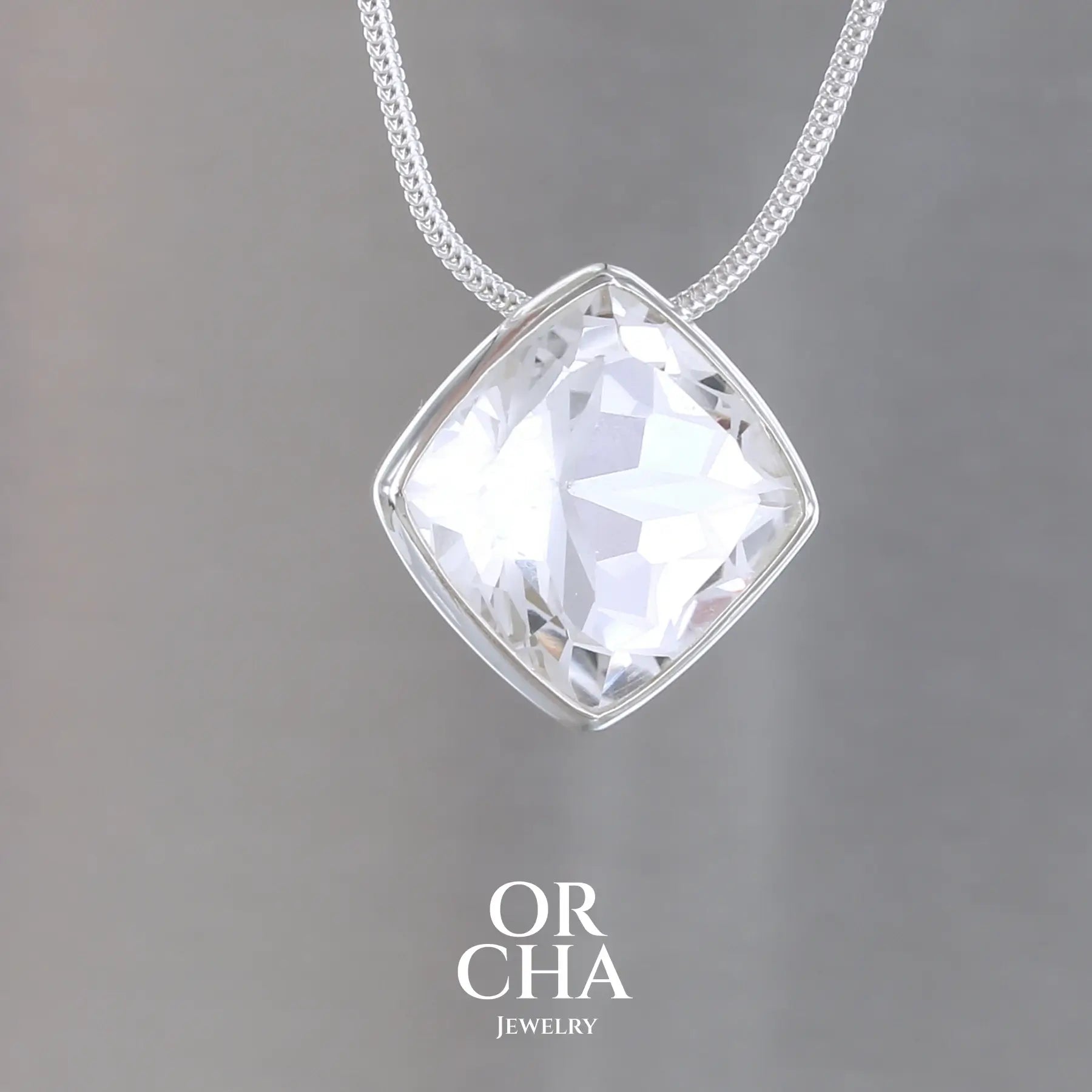collier solitaire pour femme en argent massif sertie d'un Cristal de roche gravé d'une fleur de vie. Pierre facettée de forme carrée de qualité transparente, propre à l'oeil. Pierre naturelle incolore et blanche sur les parties gravées. Pendentif monté sur une chaine en argent sterling de type maille serpent de 1,2 mm d'épaisseur et de 40 cm de longueur. Bijoux unique, éthique et durable présenté dans un coffret de notre marque, prêt à offrir. Livraison offerte, certificat d'authenticité, service client.