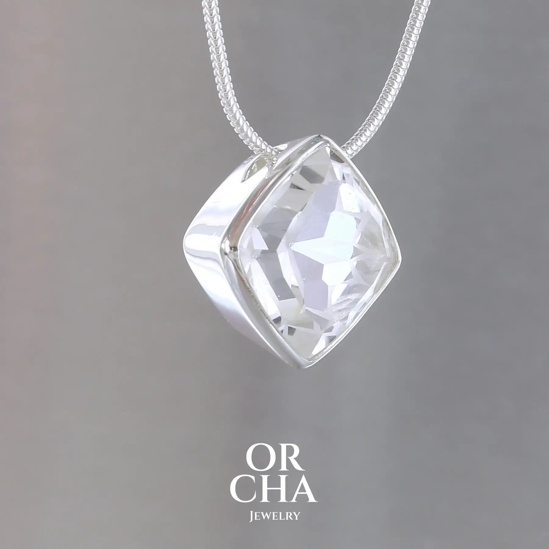 collier solitaire pour femme en argent massif sertie d'un Cristal de roche gravé d'une fleur de vie. Pierre facettée de forme carrée de qualité transparente, propre à l'oeil. Pierre naturelle incolore et blanche sur les parties gravées. Pendentif monté sur une chaine en argent sterling de type maille serpent de 1,2 mm d'épaisseur et de 40 cm de longueur. Bijoux unique, éthique et durable présenté dans un coffret de notre marque, prêt à offrir. Livraison offerte, certificat d'authenticité, service client.