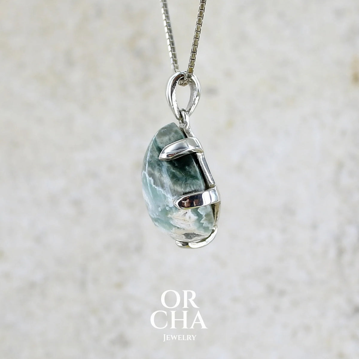 détail des griffes d'un pendentif pour femme en argent massif sertie d'un cabochon de jaspe océan de couleur nuancée de kaki et crème. Pierre opaque taillée en forme de goutte. Bijou unique par Orchajewelry