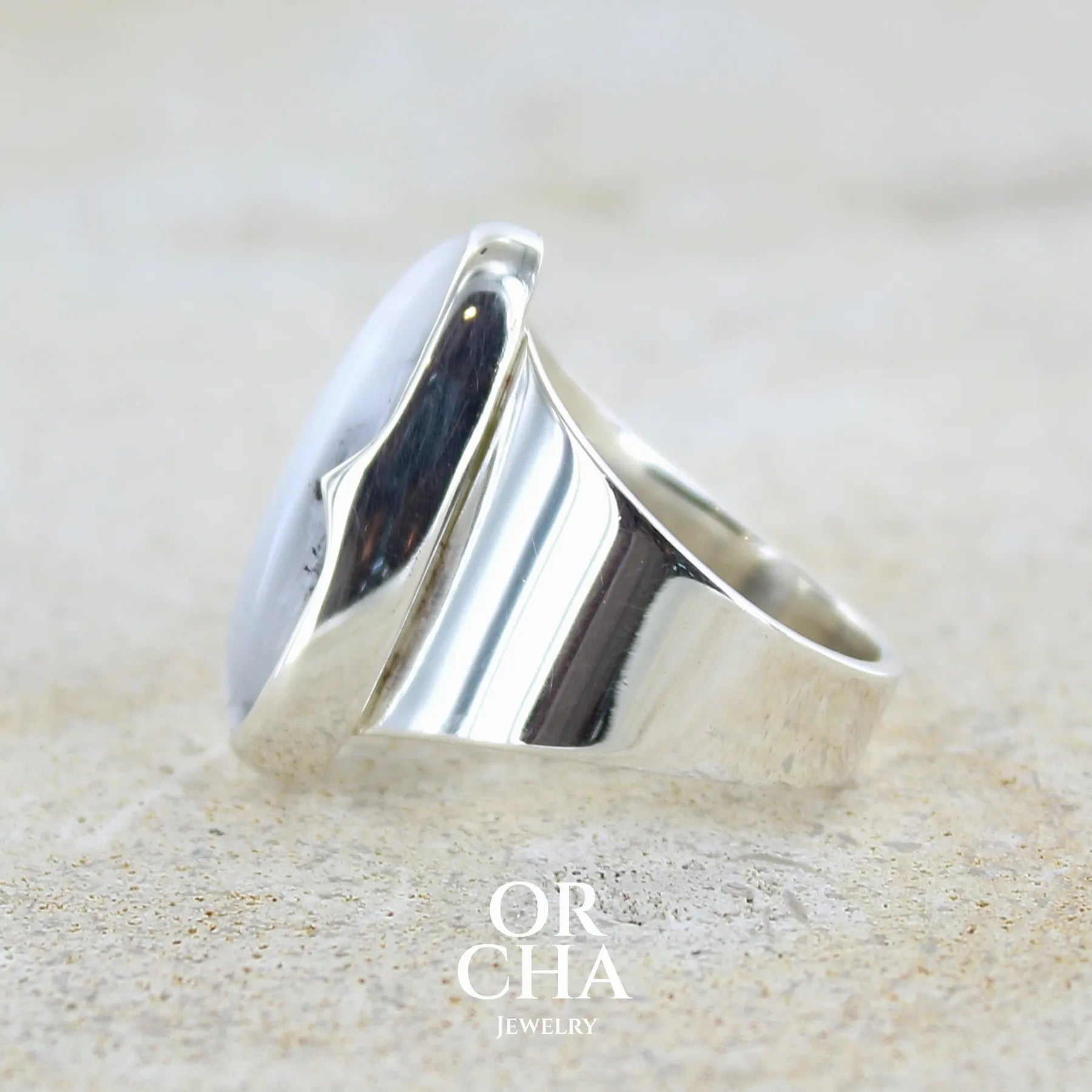 Détail du sertissage d'une bague pour femme en argent massif sertie d'un cabochon ovale d'agate dendritique de couleur blanc pur et noir. Pierre opaque translucide à inclusions paysages de dendrites de manganèse noires contrastées. Bijou unique réalisée en taille 60 par Orchajewelry