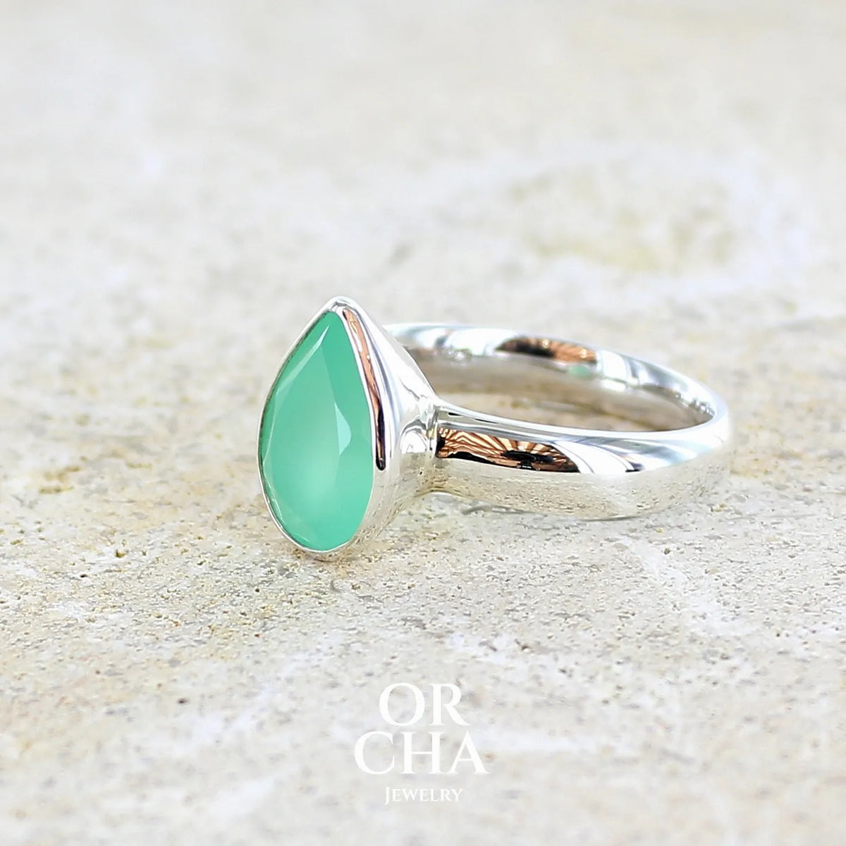 détail sertissage d'une bague pour femme en argent massif sertie d'un cabochon de chrysoprase de couleur vert émeraude pastel. Pierre translucide taillée en forme de goutte. Bijou unique réalisé en taille 56 par Orcha Jewelry