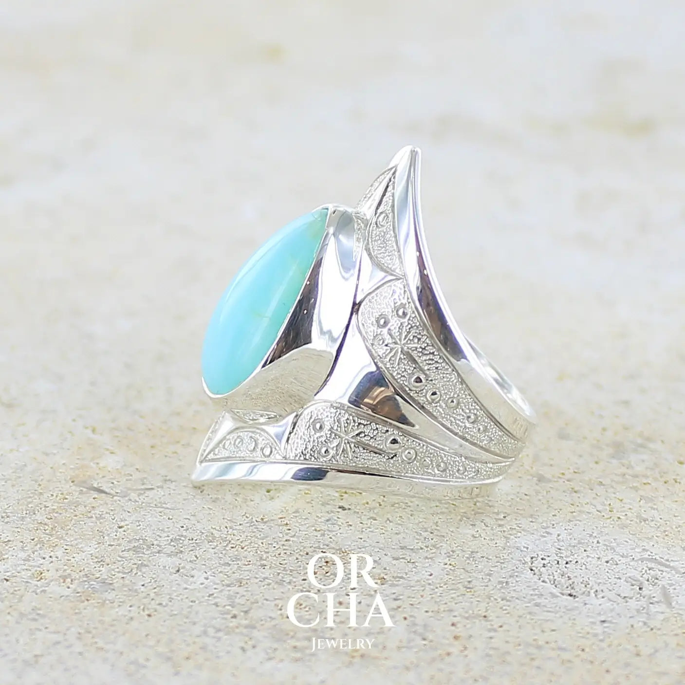 Détail de texture d'une grande Bague pour femme en argent massif, sertie d'un cabochon d'opale bleue du Pérou de couleur bleu ciel turquoise. Pierre taillée en forme de goutte. de qualité opaque. bijou unique réalisé en taille 52.