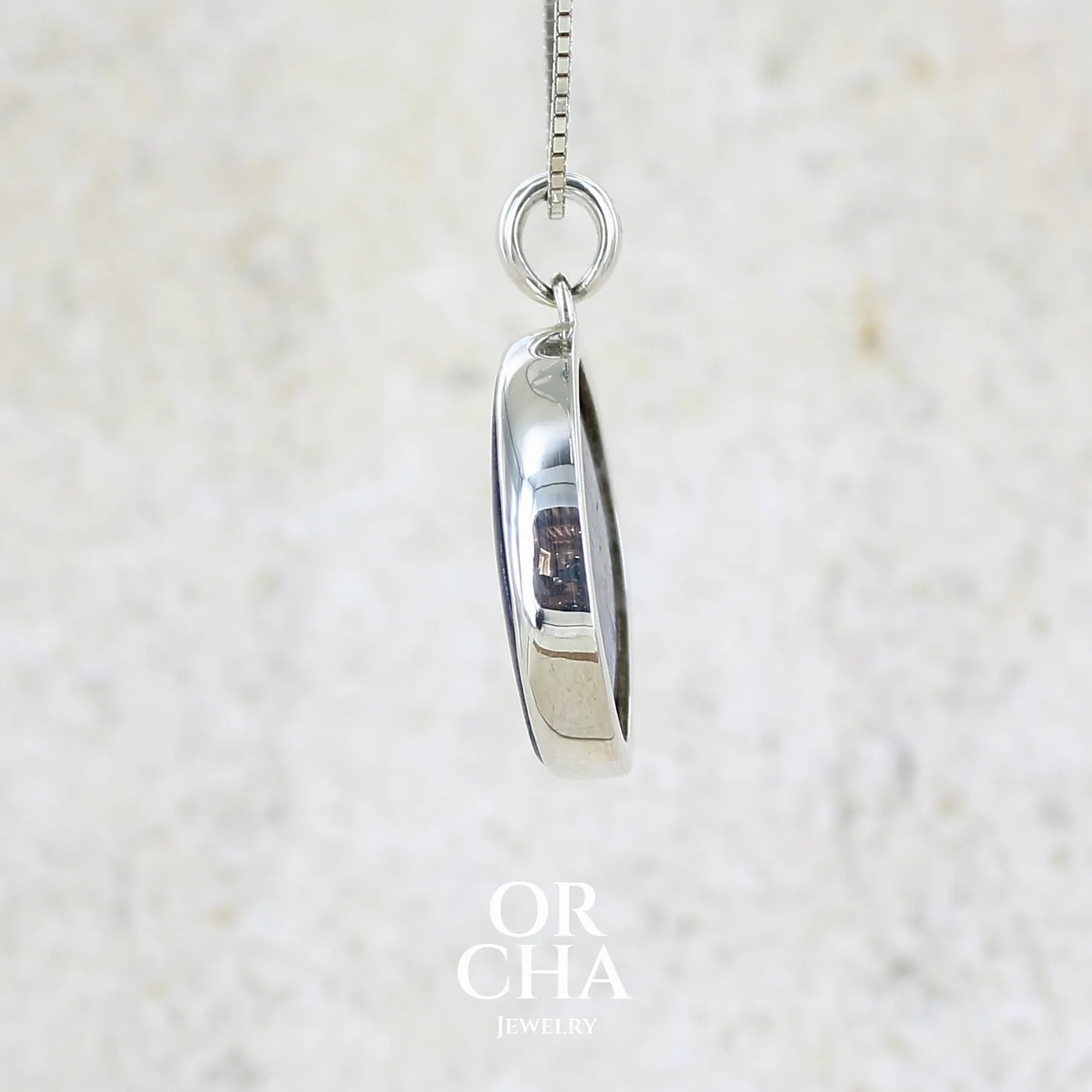 détail du sertissage d'un pendentif en argent massif serti d'un cabochon de cyanite de couleur bleue jeans nacré. Pierre de qualité opaque comportant des inclusions. Bijoux unique par Orcha Jewelry