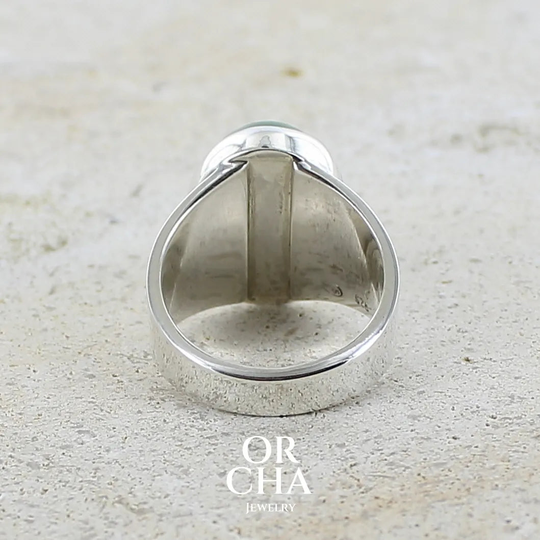 vue de dos d'une Bague pour femme en argent massif sertie d'une préhnite de couleur verte jaune clair. Pierre ovale taillée en cabochon. Pierre gemme de qualité transparente à inclusions. Bijoux unique réalisé en taille 52 par Orchajewelry.