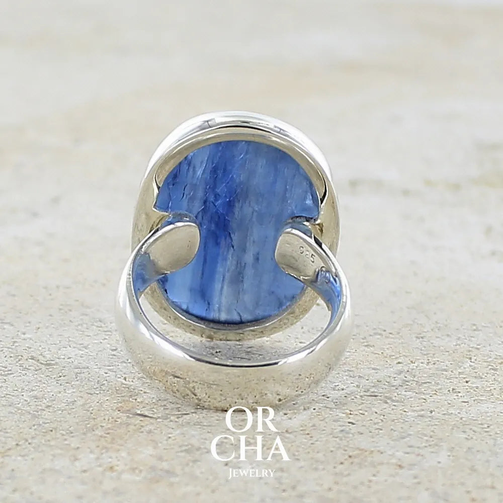 Dos d'une bague pour femme en argent massif, sertie d'un cabochon de cyanite de couleur bleue denim. Pierre transparente de forme ovale. Bijou unique réalisée en taille 52 par Orchajewelry
