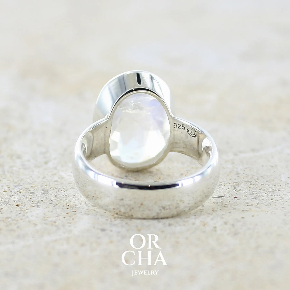 Vue de dos d'une Bague cocktail pour femme en argent massif 925 sertie d'une Labradorite blanche taillée de 6,7 carats incolore aux reflets bleutés et arc en ciel. Pierre transparente avec inclusions. Bijoux unique réalisée en taille 57 par Orchajewelry
