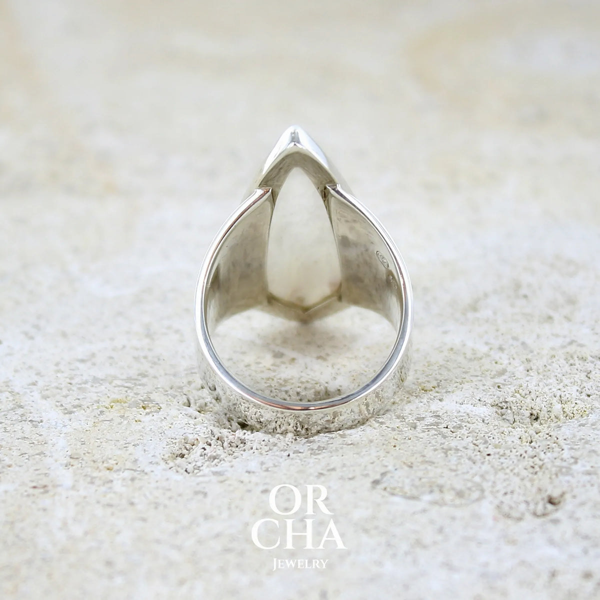 Vue de dos d'une bague contemporaine pour femme en argent massif sertie d'une scolecite blanche. Pierre naturelle de qualité opaque taillée en forme de losange. Bague unique réalisée en taille 56 par Orcha jewelry
