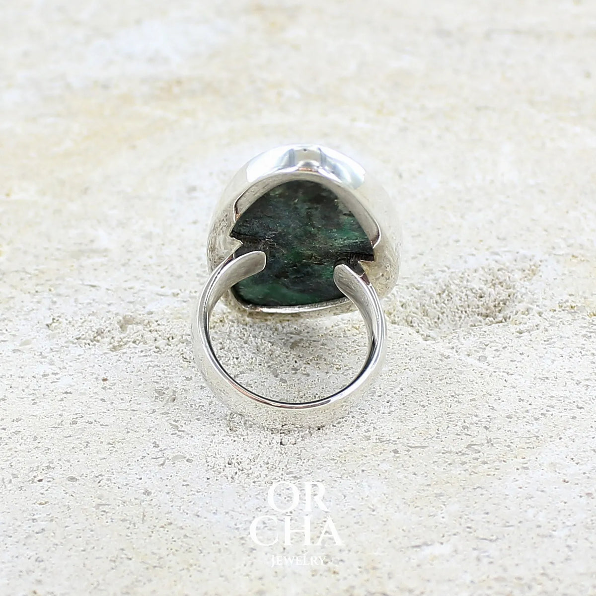 vue de dos d'une bague pour femme en argent massif sertie d'un cabochon de pierre verte scintillante à inclusions bleues et noires. Pierre de qualité opaque et de forme libre. Bijou unique réalisée en taille 56 par Orchajewelry