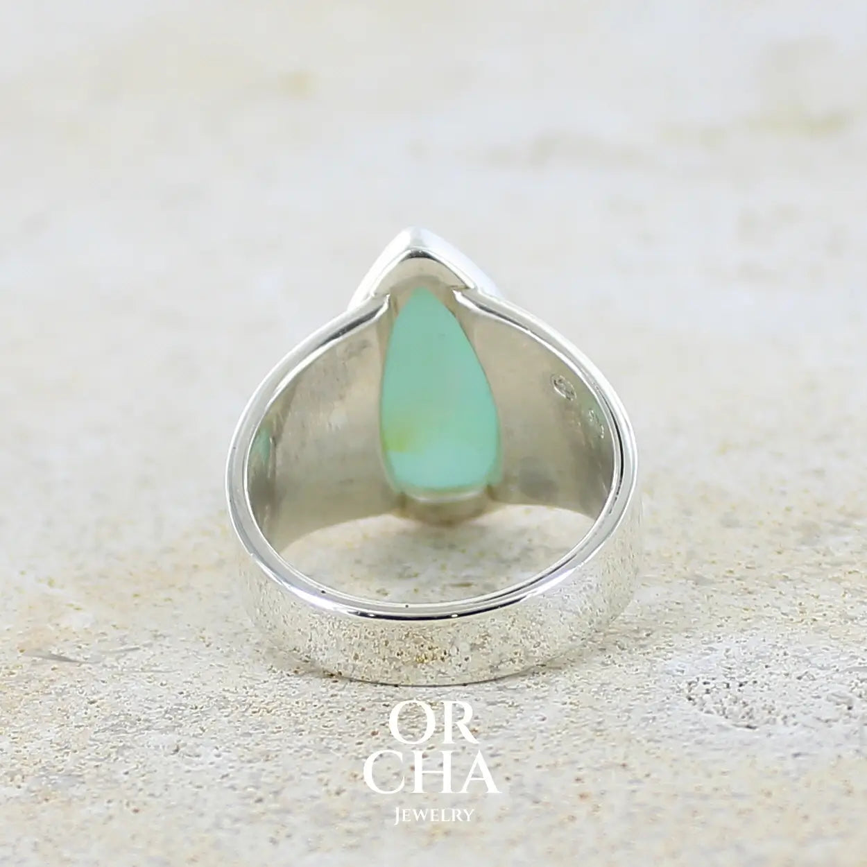 Vue de dos d'une bague pour femme en argent massif, sertie d'un cabochon d'opale bleue du Pérou de couleur bleu ciel. Pierre taillée en forme de goutte de qualité opaque. Bijou unique de taille 56