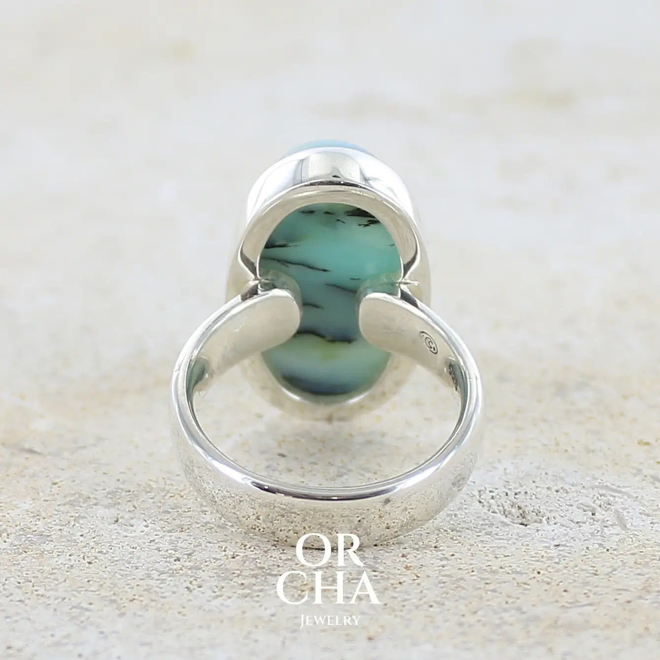 vue de dos d'une bague pour femme en argent massif, sertie d'un cabochon ovale d'opale bleue du Pérou de couleur bleu laiteux à inclusions de dendrites noires. Pierre naturelle de qualité opaque et translucide. Bijoux unique réalisé en taille 54,5 - OrchaJewelry