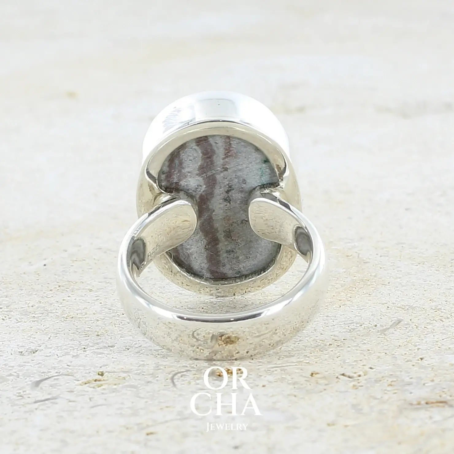 Vue de dos d'une bague pour femme en argent massif sertie d'un magnifique gemsilica druzy: chrysocale silicifiée recouverte de fins cristaux de quartz scintillants. Pierre de qualité opaque taillée en tranche de forme ovale. Pierre naturelle originaire de République dominicaine du Congo de couleur bleu clair turquoise. Bague réalisée en taille 58,5. Bijoux unique, éthique et durable présenté dans un coffret de notre marque, prêt à offrir. Livraison offerte, certificat d'authenticité, service client.