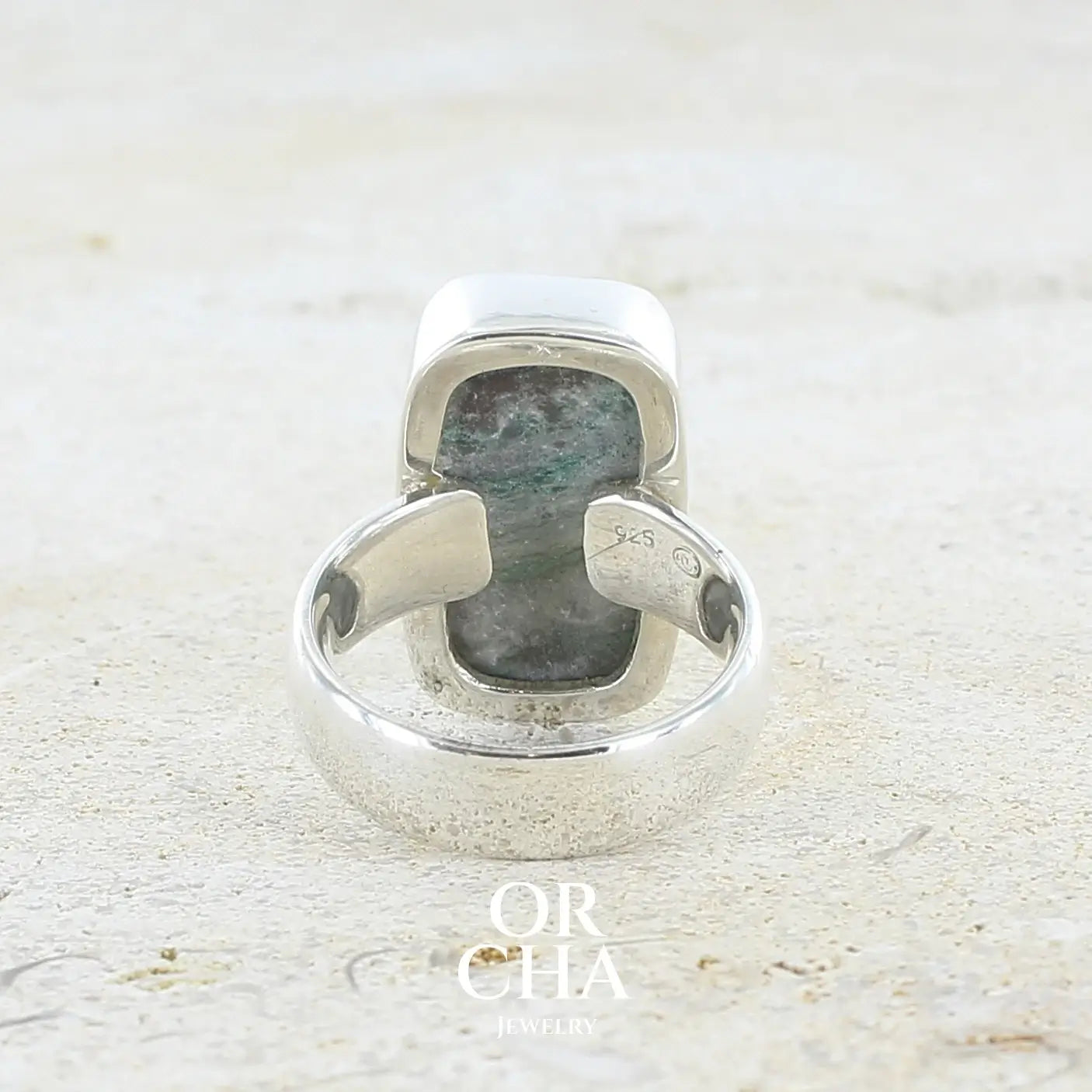 Vue de dos d'une bague pour femme en argent massif sertie d'un magnifique gemsilica druzy: chrysocale solidifiée recouverte de fins cristaux de quartz scintillant. Pierre de qualité opaque taillée en tranche de forme rectangulaire. Pierre naturelle originaire de République dominicaine du Congo de couleur turquoise, verte et noire. Taille 56. Bijoux unique, éthique et durable présenté dans un coffret de notre marque, prêt à offrir. Livraison offerte, certificat d'authenticité, service client.