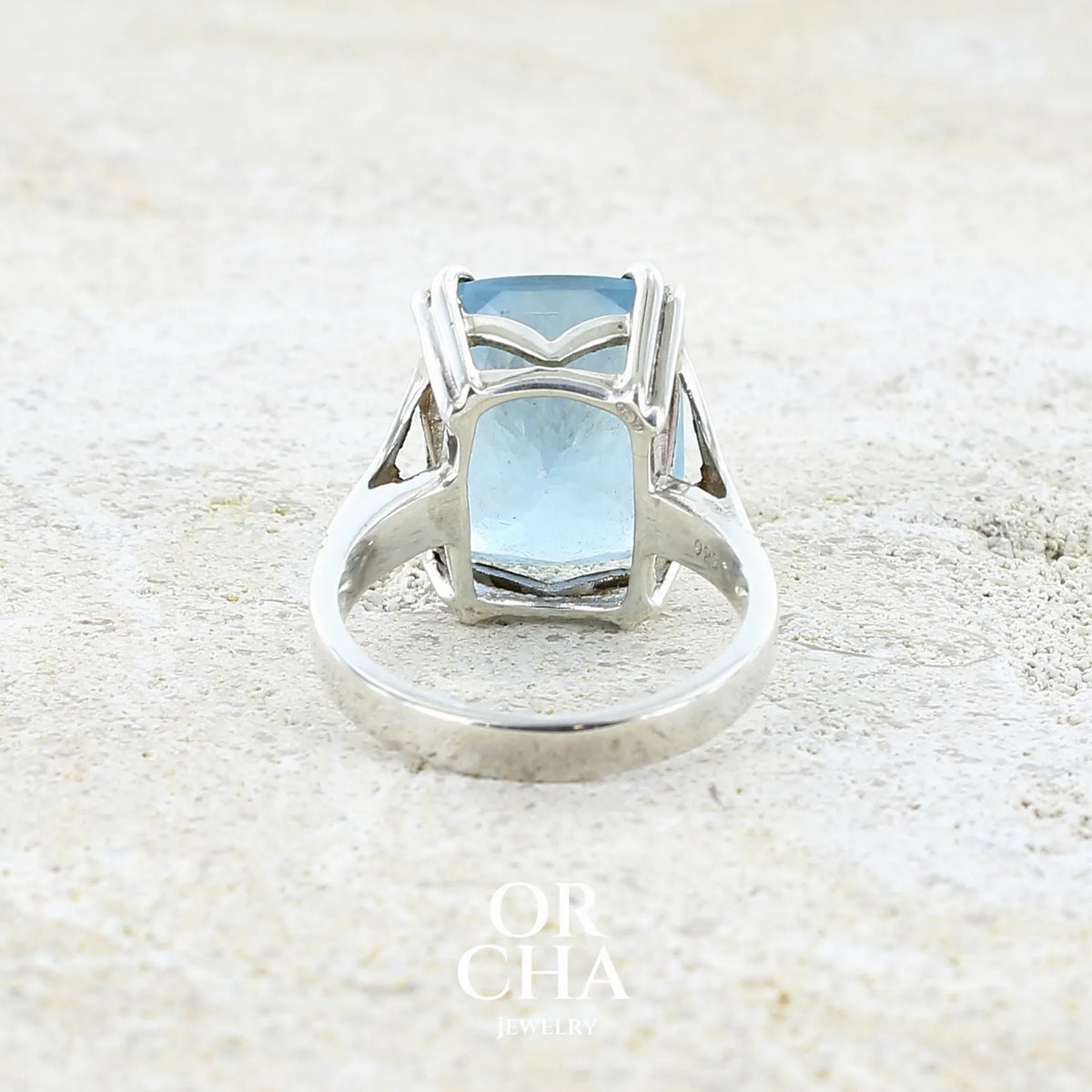 Vue de dos d'une bague pour femme en argent massif sertie d'une magnifique aigue marine taillée de 10,3 carats de couleur bleue clair intense. Pierre transparente lumineuse comportant de légères inclusions. Bijou unique réalisée en taille 54 par Orchajewelry
