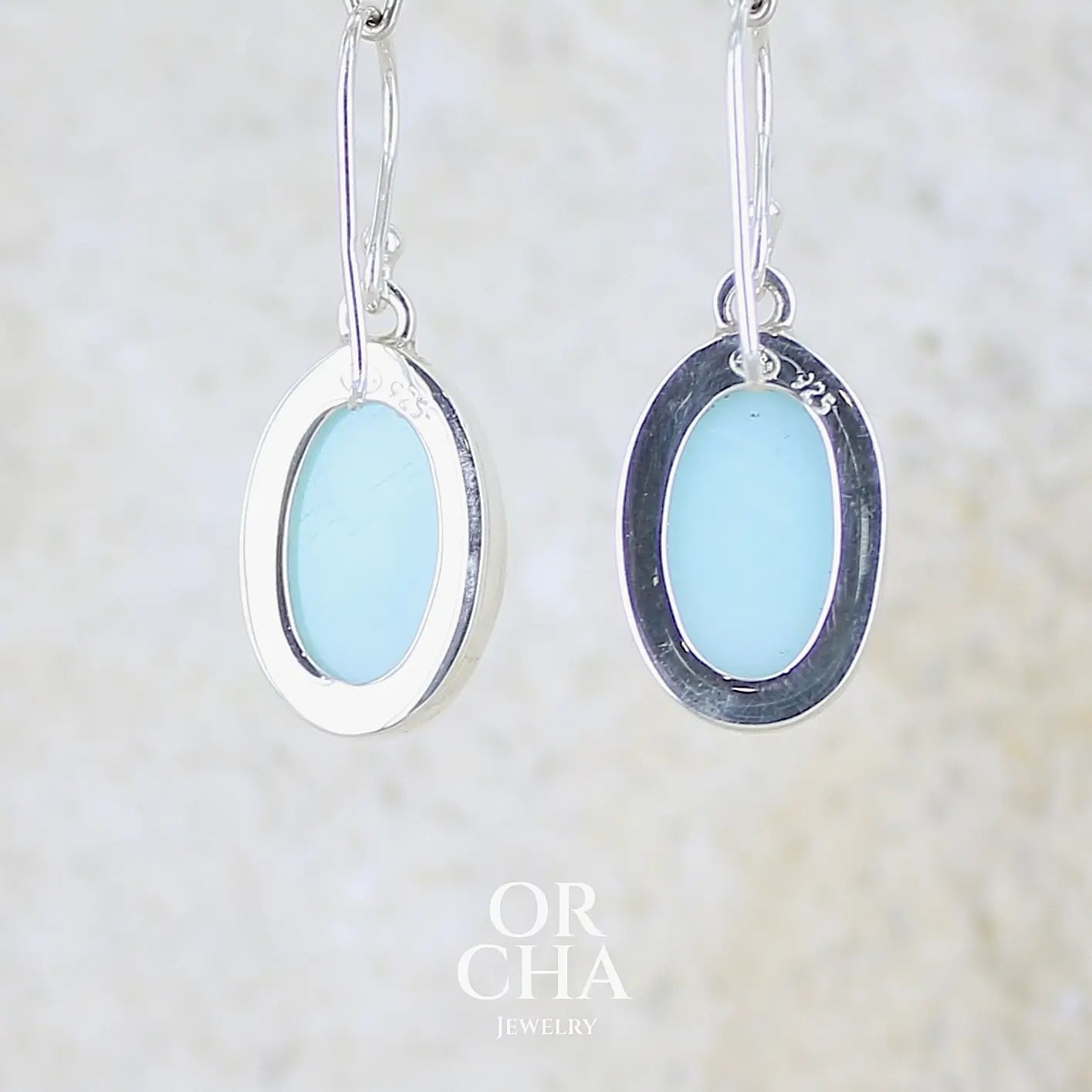 vue de dos de boucles d'oreilles pendantes en argent massif serties d'opale bleue du Pérou. Pierres cabochon taillée en ovale de qualité opaque. Pierre naturelle de couleur bleu ciel. Bijoux unique, éthique et durable présenté dans un coffret de notre marque, prêt à offrir. Livraison offerte, certificat d'authenticité, service client.