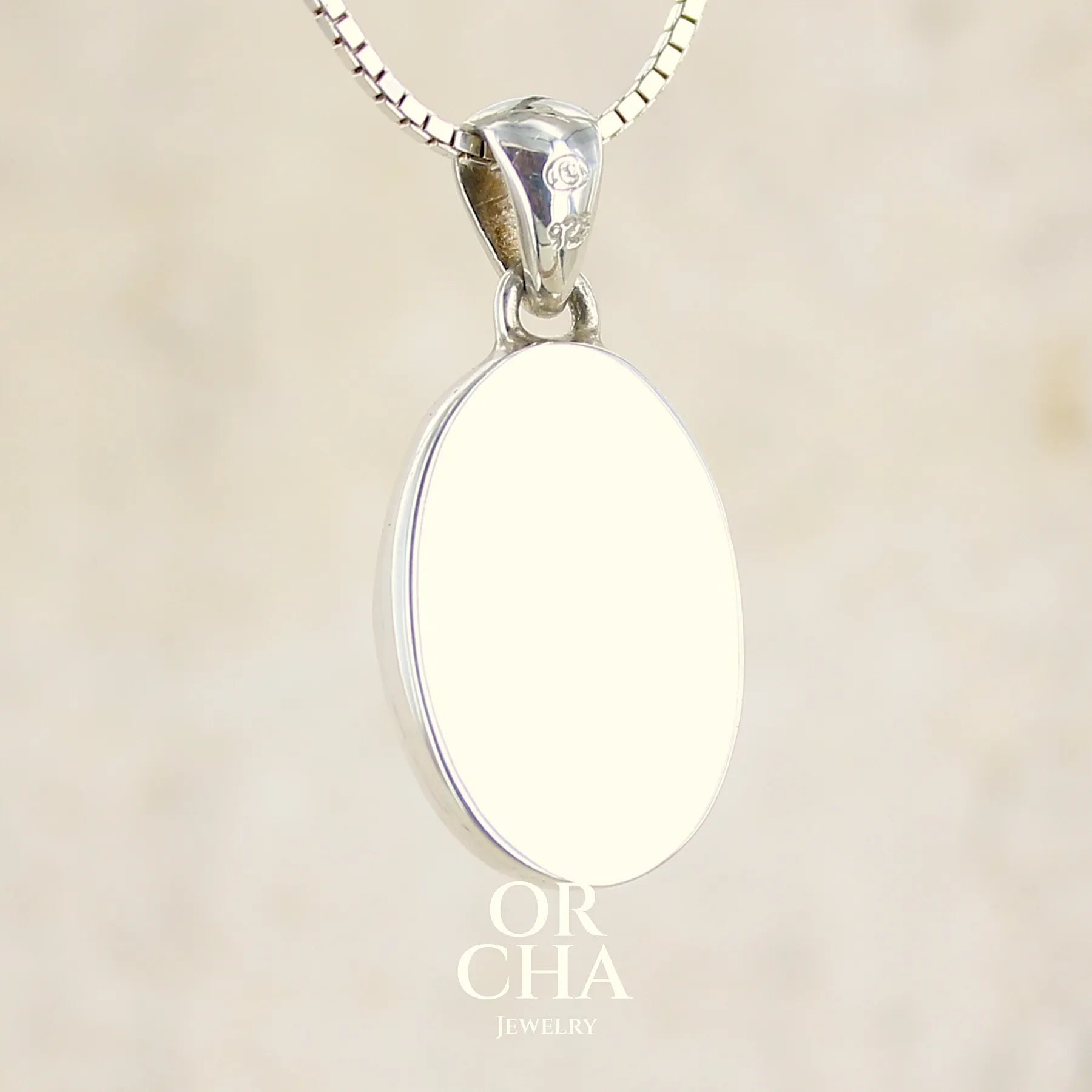 vue de dos d'un pendentif ovale en argent massif, serti d'un cabochon de calcédoine de couleur blanche verte. Pierre de qualité translucide comportant des inclusions paysages blanches. Bijoux unique par Orcha Jewelry