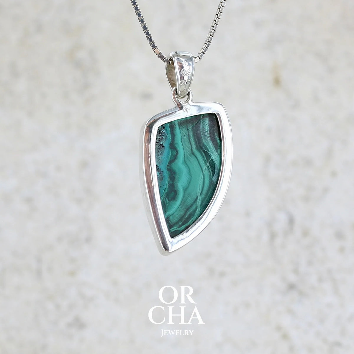 Vue de dos d'un pendentif pour femme et homme en argent massif serti d'un cabochon de Malachite de couleur verte clair et vert foncé contrasté. Cabochon en forme de dent de qualité opaque. Bijoux unique réalise par Orchajewelry