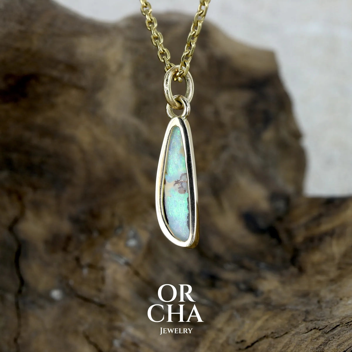 dos d'un Pendentif pour femme en or jaune massif 18k serti d'une opale cristal aux feux étoilés multicolores à dominantes vert turquoises. Cabochon de 1 carat taille en forme de goutte de qualité transparente. Bijou unique réalisé par Orchajewelry