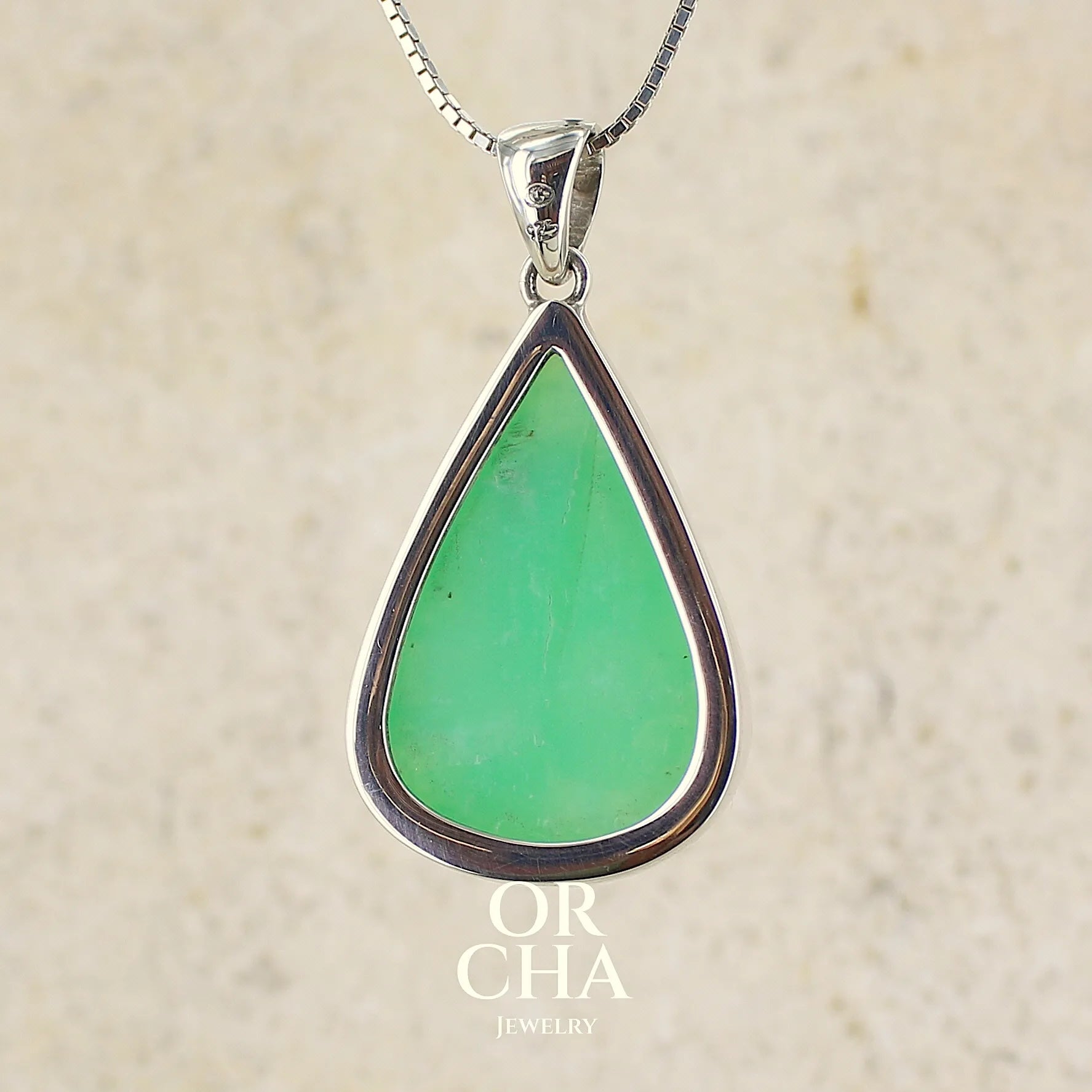 Vue de dos d'un pendentif pour femme en argent massif, sertie d'un cabochon de chrysoprase de couleur vert pomme. Cabochon de qualité translucide taillée en forme de goutte. Bijoux unique par Orcha jewelry