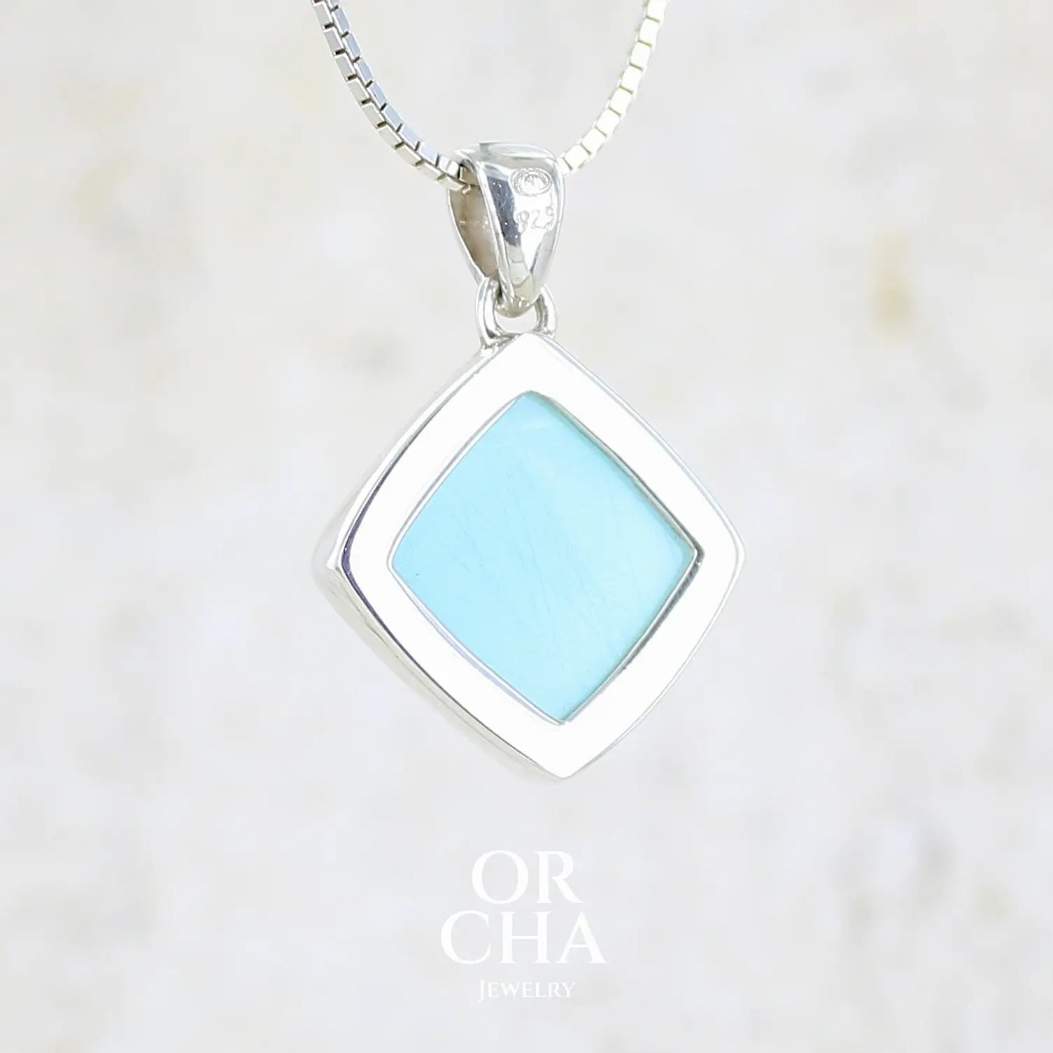 vue de dos d'un pendentif en argent massif, sertie d'un cabochon d'opale bleue du Pérou de couleur bleu ciel clair. Pierre de forme carrée. Pierre opaque. Bijoux unique, éthique et durable présenté dans un coffret de notre marque, prêt à offrir. Livraison offerte, certificat d'authenticité, service client.