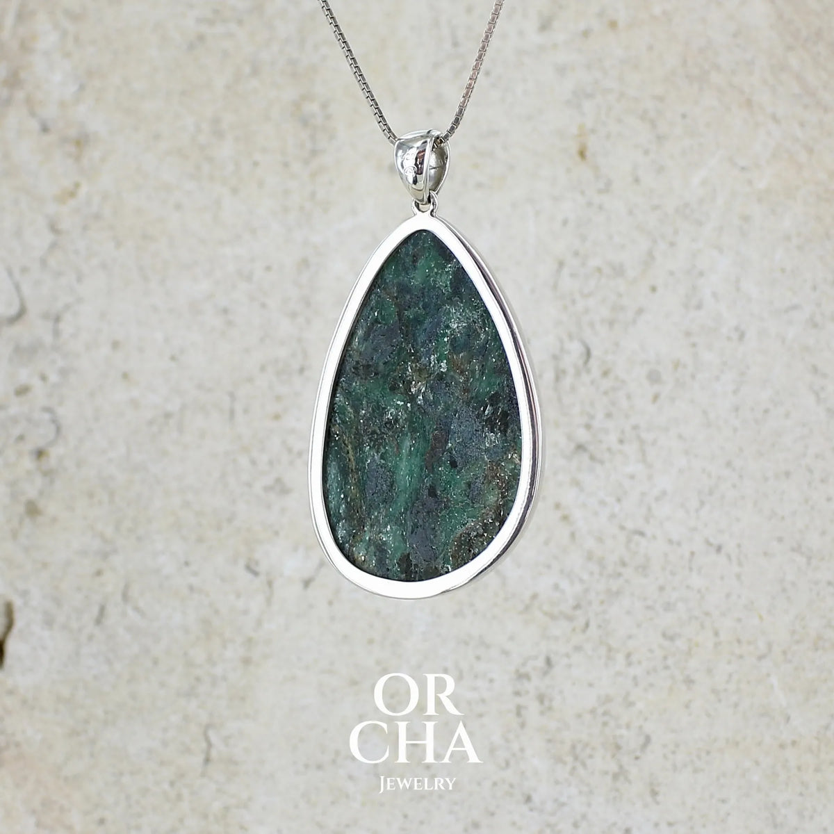 vue de dos d'un pendentif pour femme en argent massif serti d'une pierre verte scintillante à inclusions bleutées et noires. Cabochon de forme libre de qualité opaque. Bijou unique réalisé par Orchajewelry