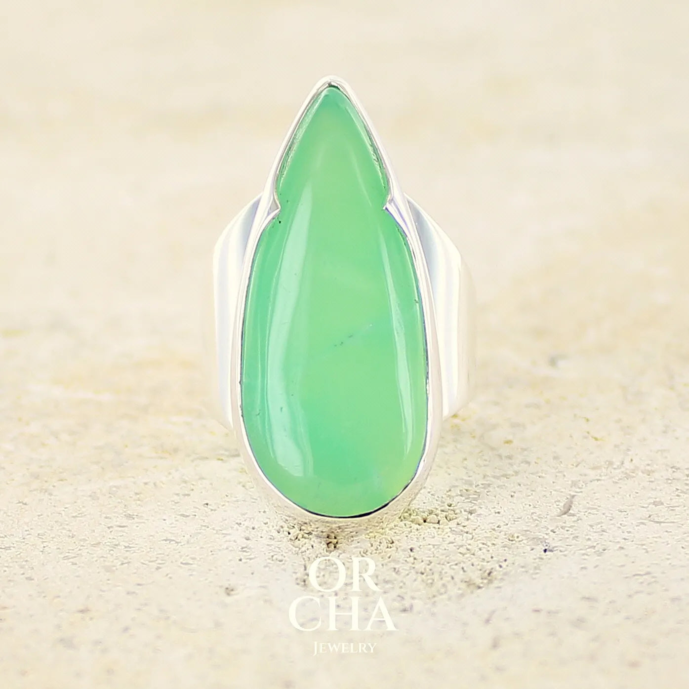 Grande Bague pour femme en argent massif, sertie d'un cabochon de chrysoprase. Pierre naturelle de couleur verte taillée en forme de goutte de qualité translucide. Bijoux unique réalisé en taille 54 par Orchajewelry