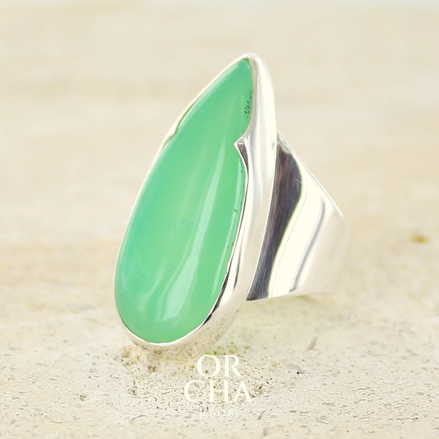 Grande Bague pour femme en argent massif, sertie d'un cabochon de chrysoprase. Pierre naturelle de couleur verte taillée en forme de goutte de qualité translucide. Bijoux unique réalisé en taille 54 par Orchajewelry