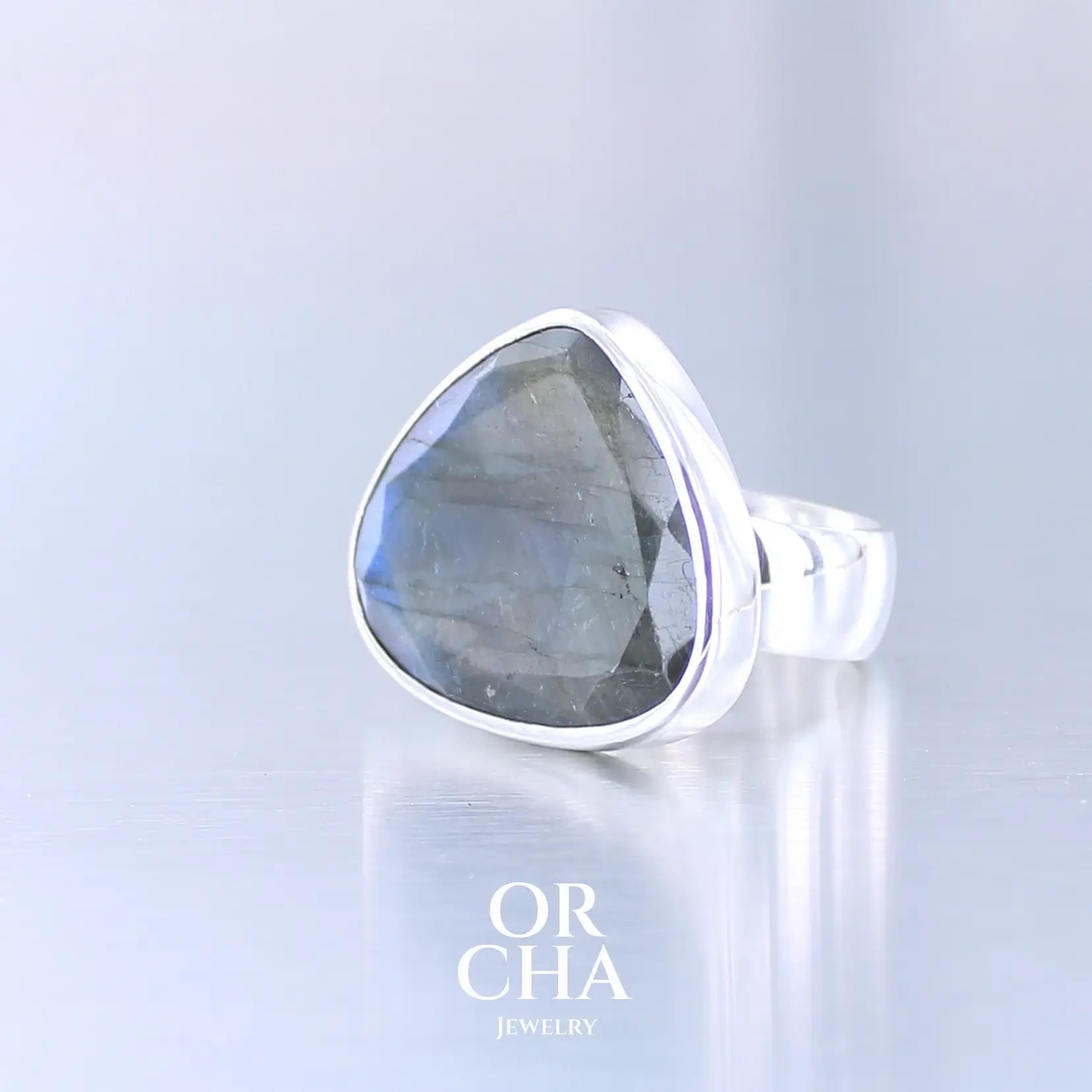 Bague pour femme en argent massif sertie d'une labradorite aux reflets bleus et verts selon la lumière. Pierre facettée naturelle translucide présentant des inclusions fréquents sur ce type de pierre. Taille 56. Bijoux unique, éthique et durable présenté dans un coffret de notre marque, prêt à offrir. Livraison offerte, certificat d'authenticité, service client.