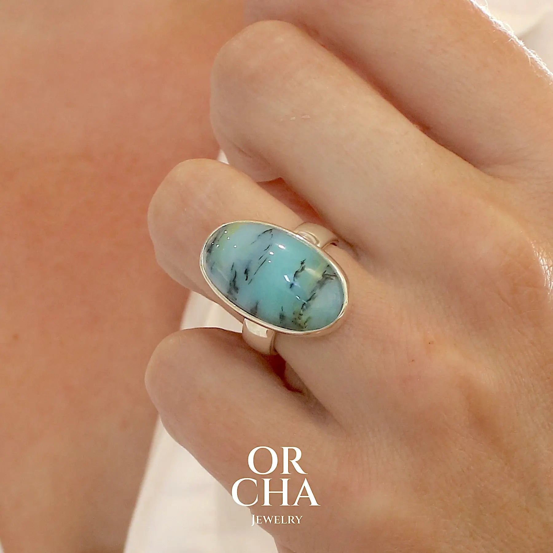 modele Bague pour femme en argent massif, sertie d'un cabochon ovale d'opale bleue du Pérou de couleur bleu laiteux à inclusions de dendrites noires. Pierre naturelle de qualité opaque et translucide. Bijoux unique réalisé en taille 54,5 - OrchaJewelry