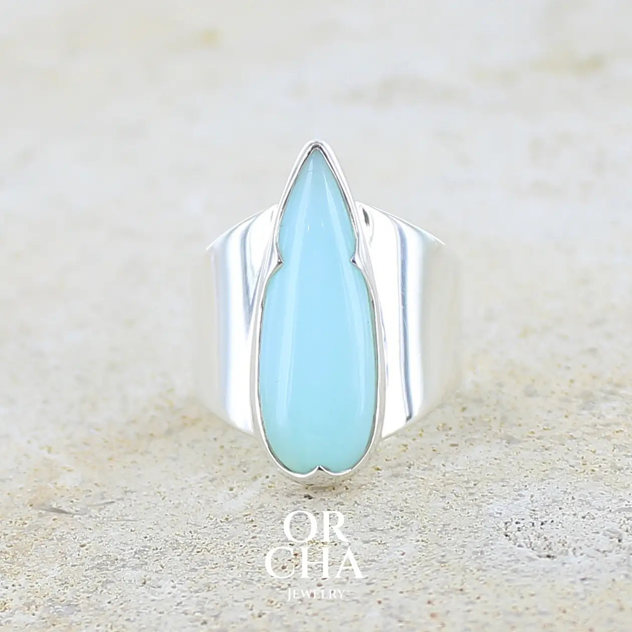 Bague pour femme en argent massif, sertie d'un cabochon d'opale bleue du Pérou de couleur bleu ciel. Pierre taillée en forme de goutte longiligne, de qualité opaque. Bijou unique réalisé en taille 53,5.