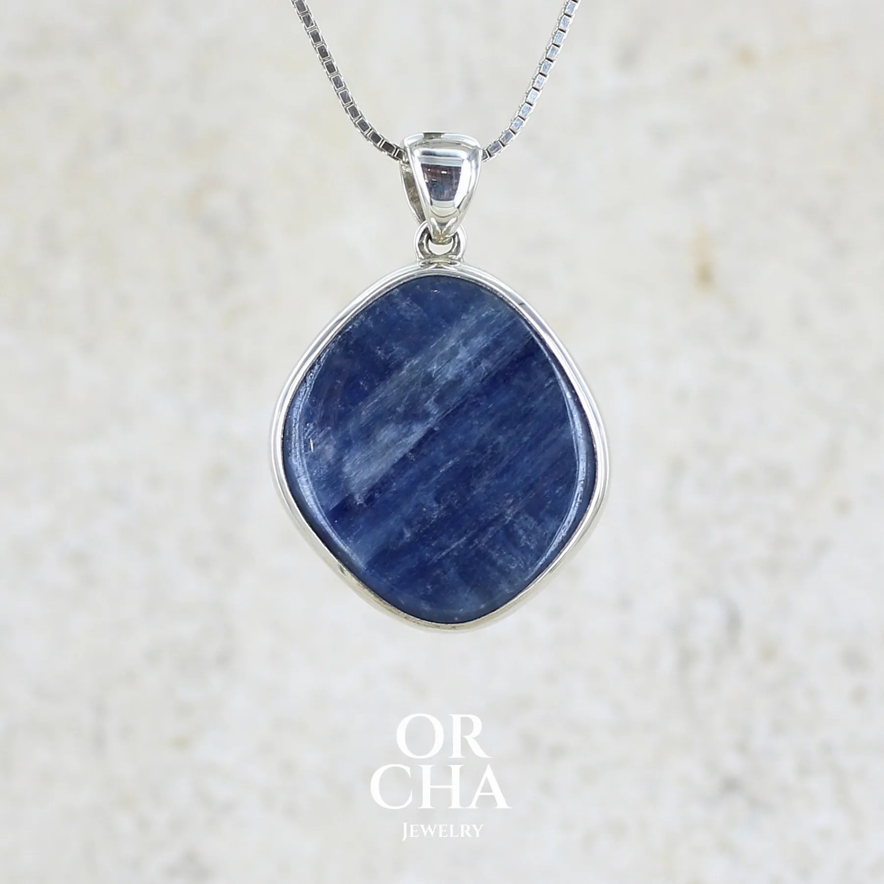 Pendentif en argent massif serti d'un cabochon de cyanite de couleur bleue jeans nacré. Pierre de qualité opaque comportant des inclusions. Bijoux unique par Orcha Jewelry
