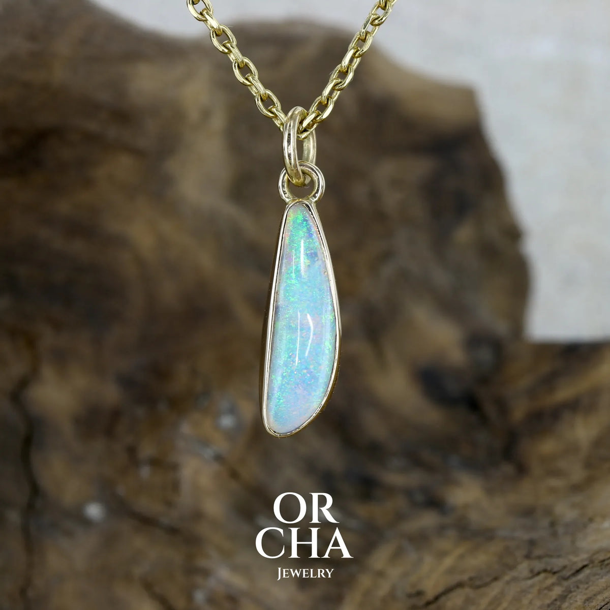 Pendentif pour femme en or jaune massif 18k serti d'une opale cristal aux feux étoilés multicolores à dominantes vert turquoises. Cabochon de 1 carat taille en forme de goutte de qualité transparente. Bijou unique réalisé par Orchajewelry