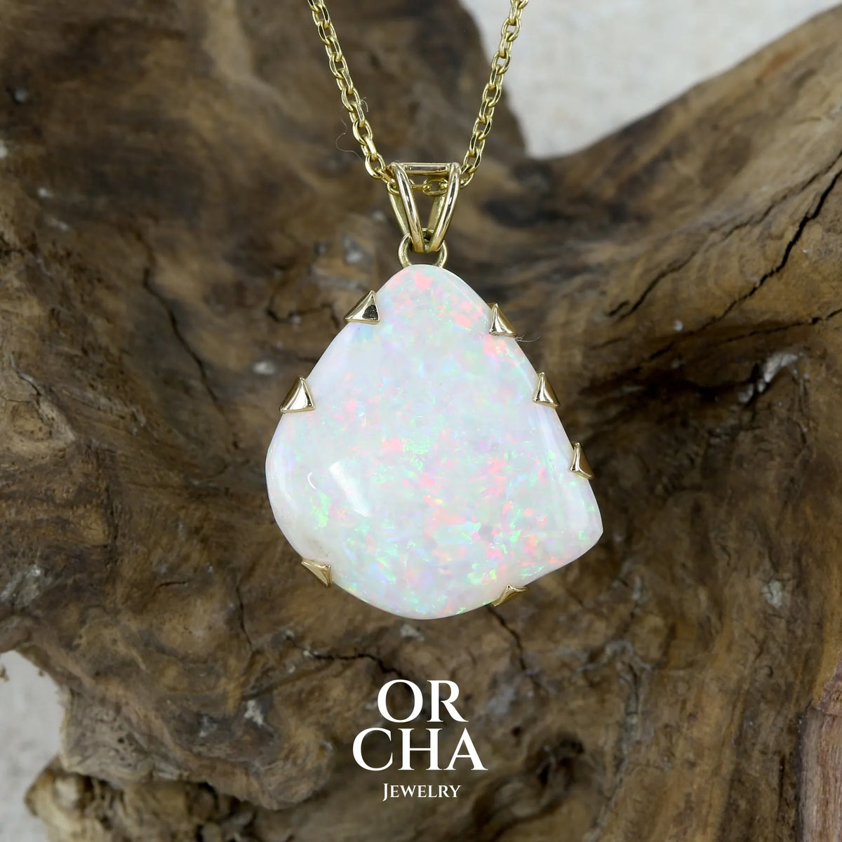 Pendentif pour femme en or jaune 18k serti d'une opale blanche massive de 17 carats aux feux multicolores. Pierre naturelle cabochon de forme irrégulière sertis de griffes. A noter: présence de roche mère de couleur crème au dos de la pierre. Bijoux unique par Orcha jewelry