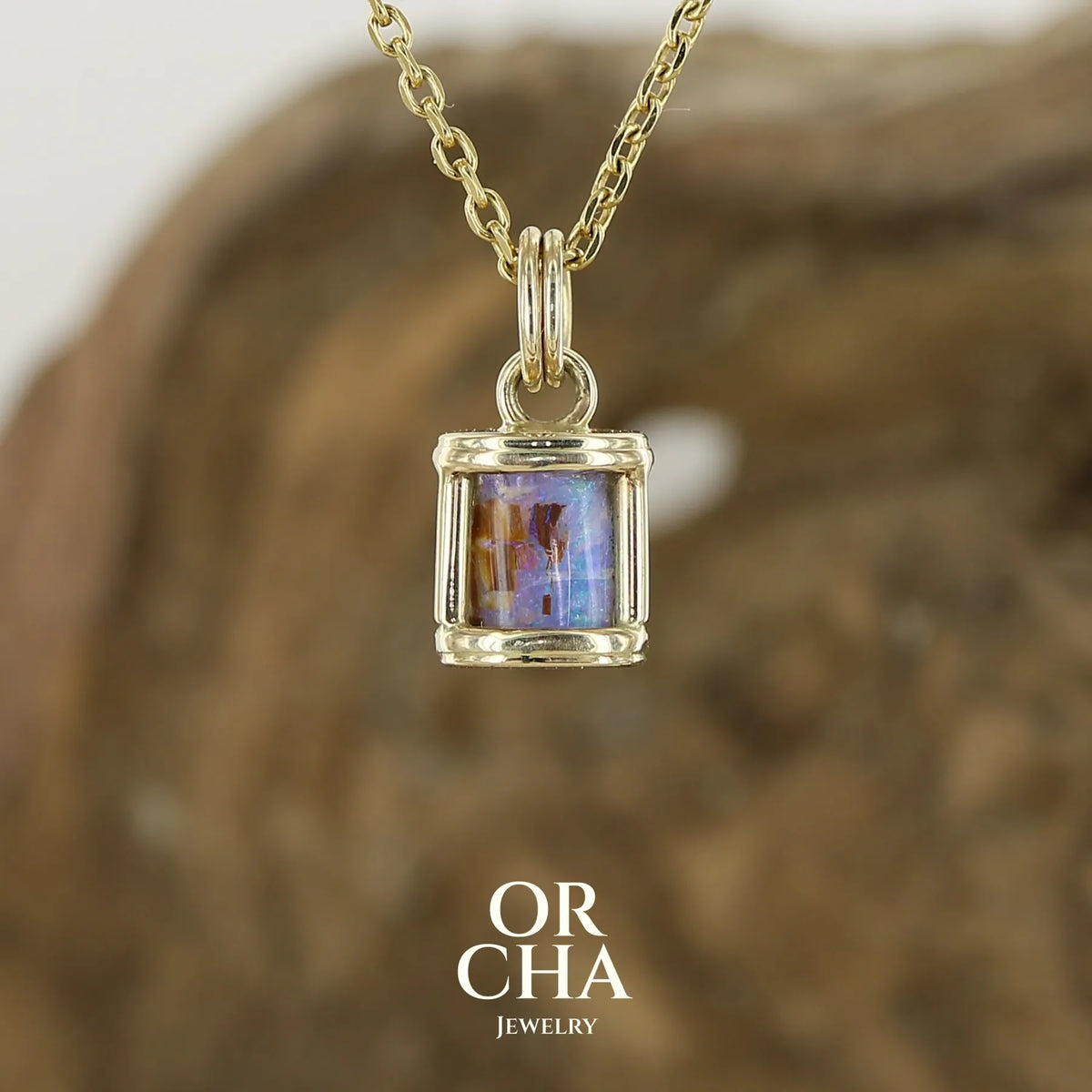 Pendentif pour femme en or jaune massif 14k serti d'une opale pipe aux feux multicolores à dominantes bleu et violet. Specimen cylindrique d'opale rarement proposé en bijouterie. Bijou unique par par Orchajewelry