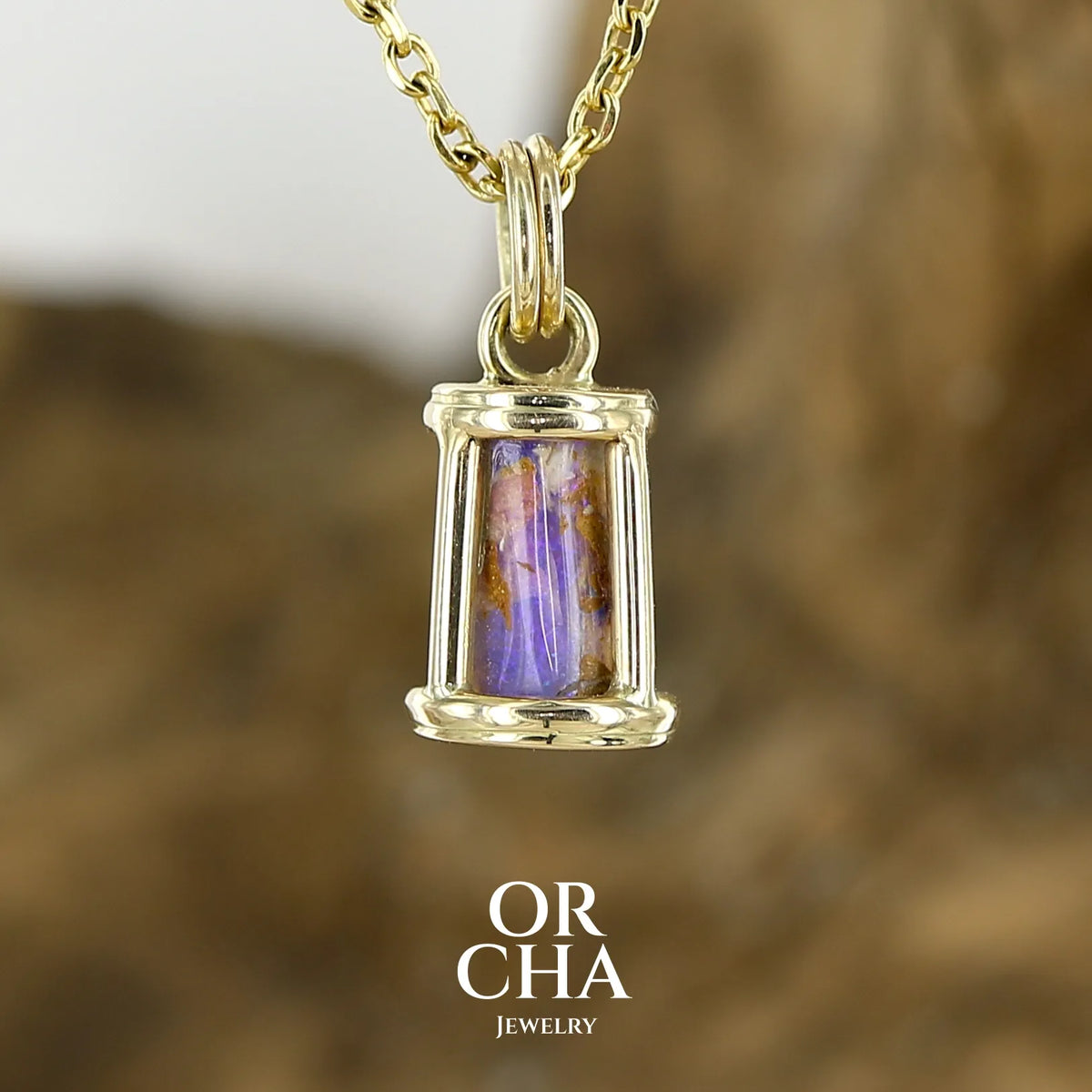 Pendentif pour femme en or jaune massif 14k serti d'une opale pipe aux feux multicolores à dominantes bleu et violet. Specimen cylindrique, sertissage cage, opale rarement proposé en bijouterie. Bijou unique par par Orchajewelry