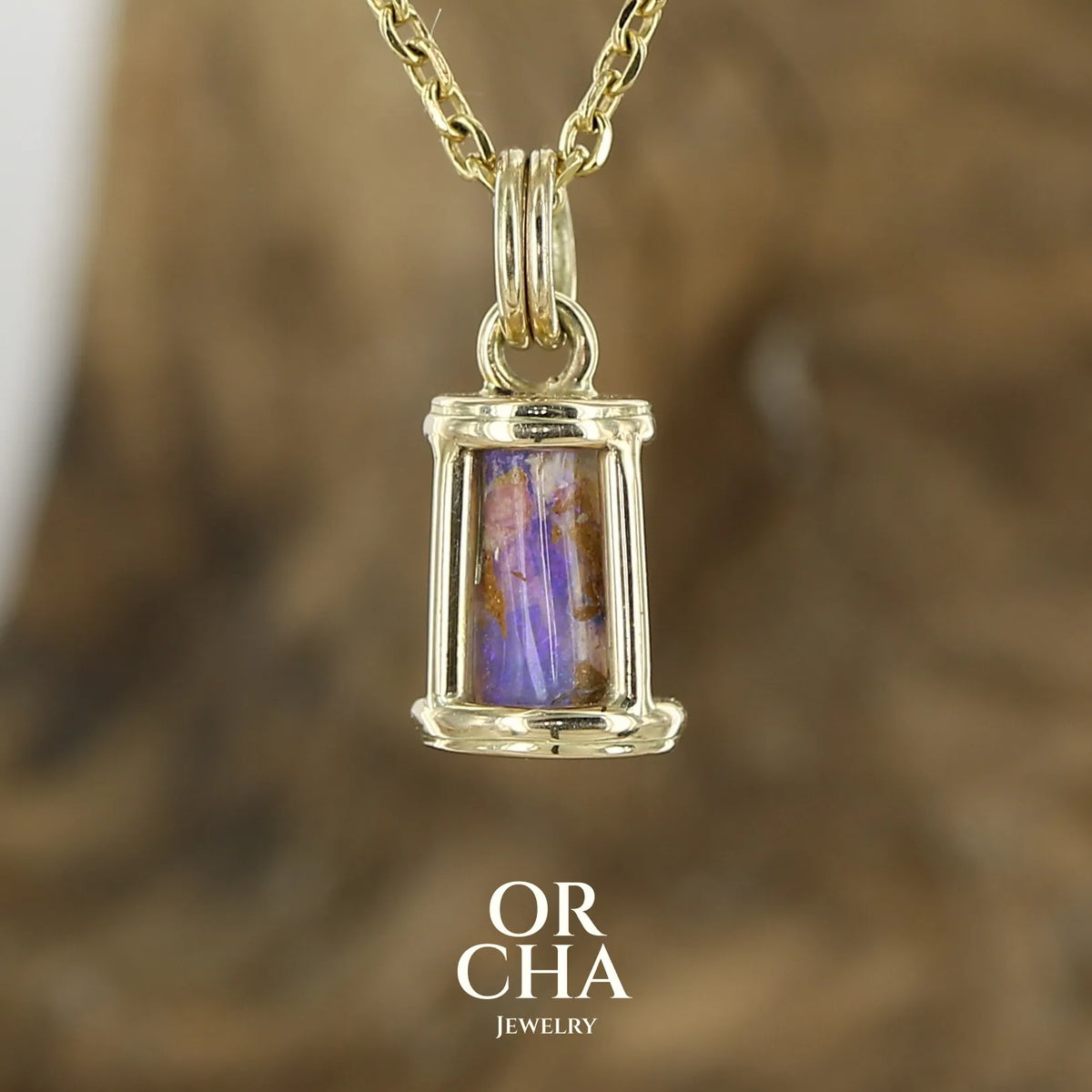 Pendentif pour femme en or jaune massif 14k serti d'une opale pipe aux feux multicolores à dominantes bleu et violet. Specimen cylindrique, sertissage cage, opale rarement proposé en bijouterie. Bijou unique par par Orchajewelry