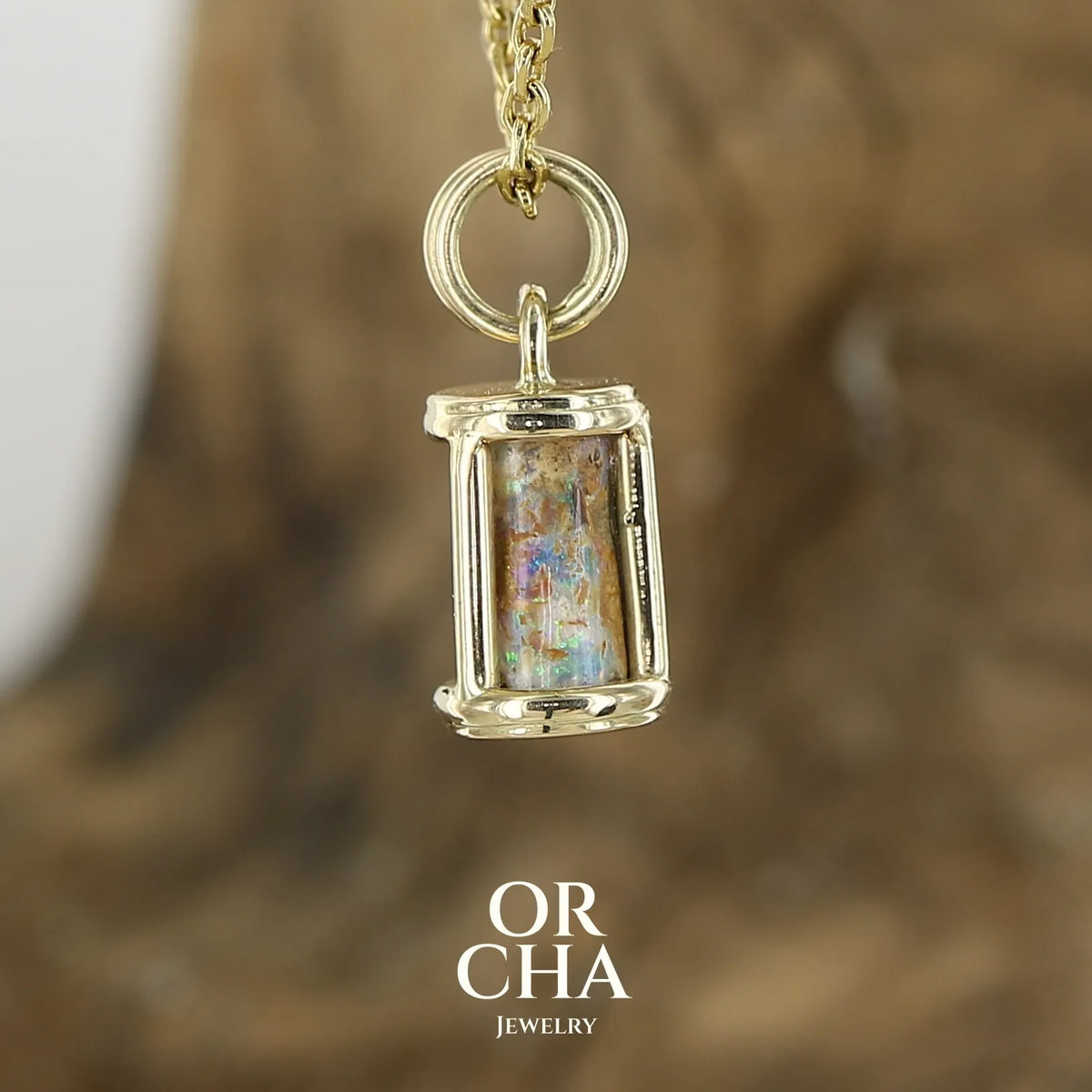 Pendentif pour femme en or jaune massif 14k serti d'une opale pipe aux feux multicolores à dominantes bleu et violet. Specimen cylindrique, sertissage cage, opale rarement proposé en bijouterie. Bijou unique par par Orchajewelry