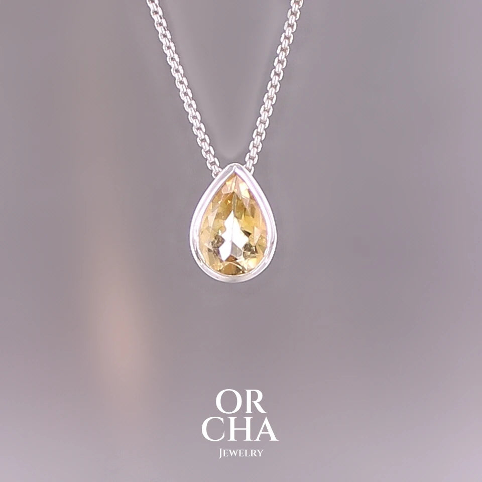 Collier solitaire pour femme en argent massif serti d'une Citrine. Pierre au nuance de couleur jaune doré lumineux, pierre facettée en forme de goutte, qualité transparente propre à l'oeil. Pendentif monté sur une chaine en argent sterling de type maille vénitienne de 1,3 mm d'épaisseur et de 40 cm de longueur. Bijoux unique, éthique et durable présenté dans un coffret de notre marque, prêt à offrir. Livraison offerte, certificat d'authenticité, service client. Par Orcha Jewelry
