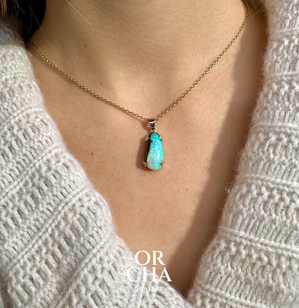 Pendentif pour femme en or 9k et argent massif serti d'une opale boulder cristal aux feux étoilés multicolores à dominantes bleu turquoise. Cabochon de 7 carat taillé en forme de goutte de qualité translucide. Opale massive australienne. Bijou unique réalisé par Orchajewelry