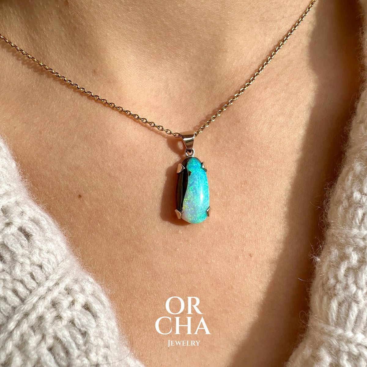 Pendentif pour femme en or 9k et argent massif serti d'une opale boulder cristal aux feux étoilés multicolores à dominantes bleu turquoise. Cabochon de 7 carat taillé en forme de goutte de qualité translucide. Opale massive australienne. Bijou unique réalisé par Orchajewelry