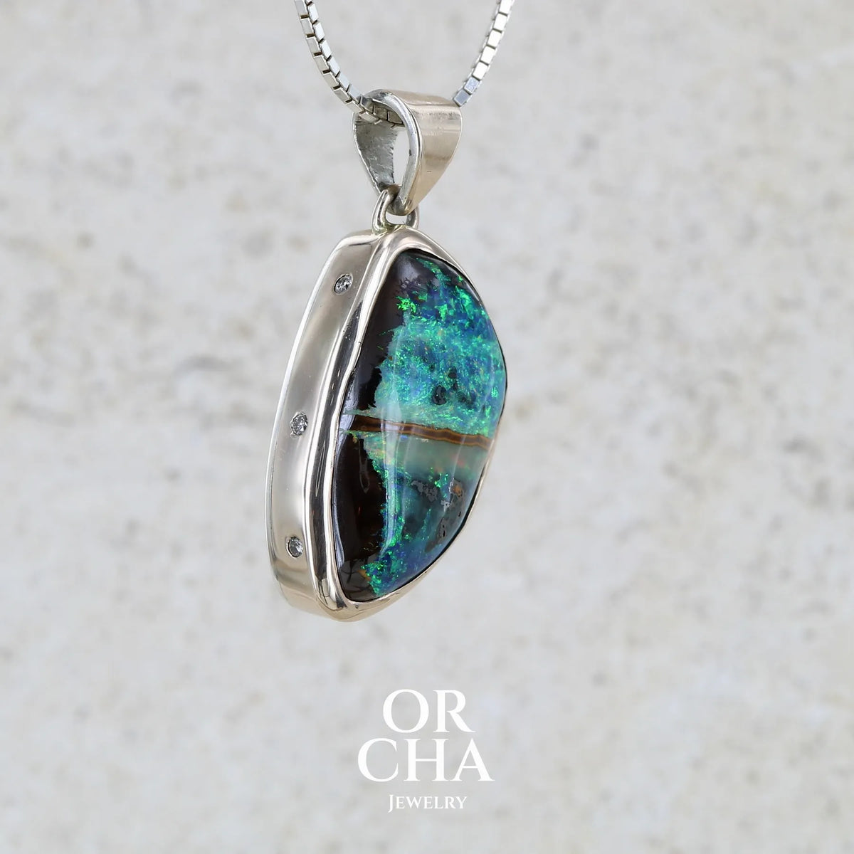 Pendentif pour femme en or 9k massif et argent massif 925 serti d'une opale boulder aux feux multicolores à dominantes bleu turquoise et vert et de six diamants. Pierre cabochon de qualité opaque taillée en forme d'aile. Bijou unique par Orchajewelry