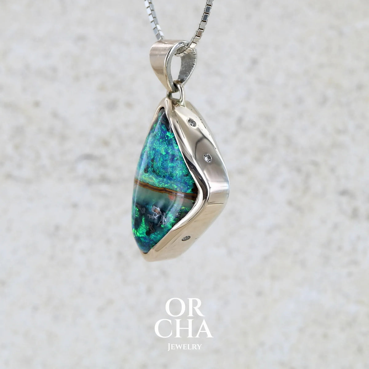 Pendentif pour femme en or 9k massif et argent massif 925 serti d'une opale boulder aux feux multicolores à dominantes bleu turquoise et vert et de six diamants. Pierre cabochon de qualité opaque taillée en forme d'aile. Bijou unique par Orchajewelry