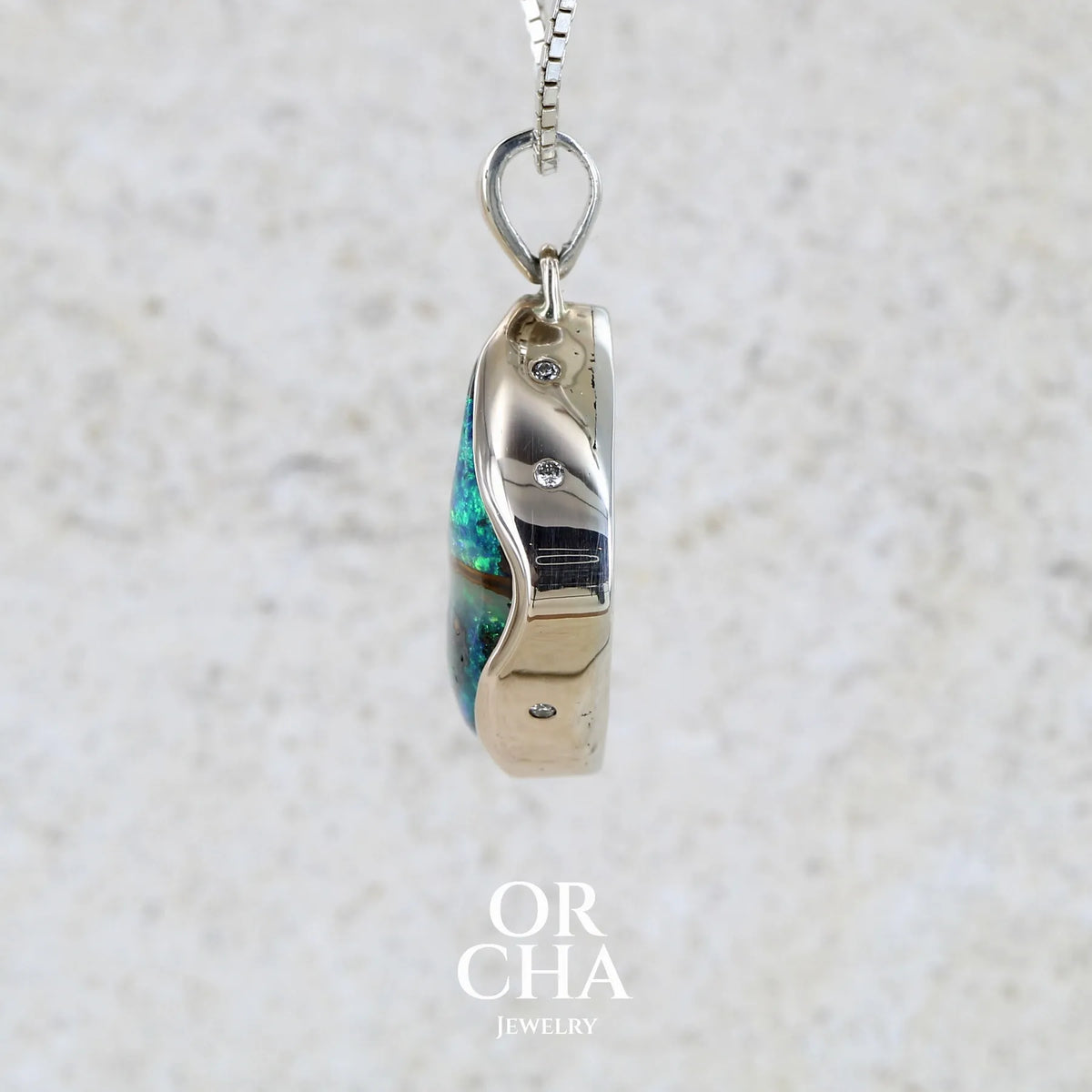 Pendentif pour femme en or 9k massif et argent massif 925 serti d'une opale boulder aux feux multicolores à dominantes bleu turquoise et vert et de six diamants. Pierre cabochon de qualité opaque taillée en forme d'aile. Bijou unique par Orchajewelry