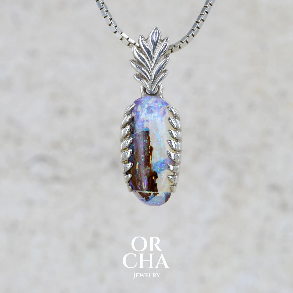 Pendentif pour femme en argent massif 925 serti d'une opale cristal aux feux étoilés multicolores à dominante bleu violet et vert. Cabochon de 3,2 carats taillé de forme oval de qualité transparente. Bijou unique réalisé par Orchajewelry