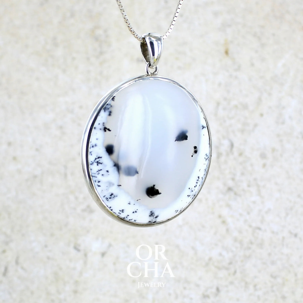 Pendentif pour femme en argent massif sertie d'un cabochon rond d'agate dendritique de couleur blanc pur et noir. Pierre opaque à translucide à inclusions paysages de dendrites de manganèse noires contrastées. Bijou unique réalisé par Orchajewelry
