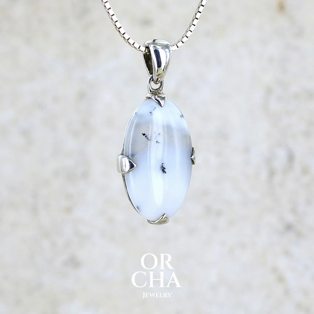 Pendentif pour femme en argent massif sertie d'un cabochon de forme ovale d'agate dendritique de couleur blanc pur et noir. Pierre opaque à translucide à inclusions paysages de dendrites de manganèse noires contrastées. Bijou unique réalisé par Orchajewelry